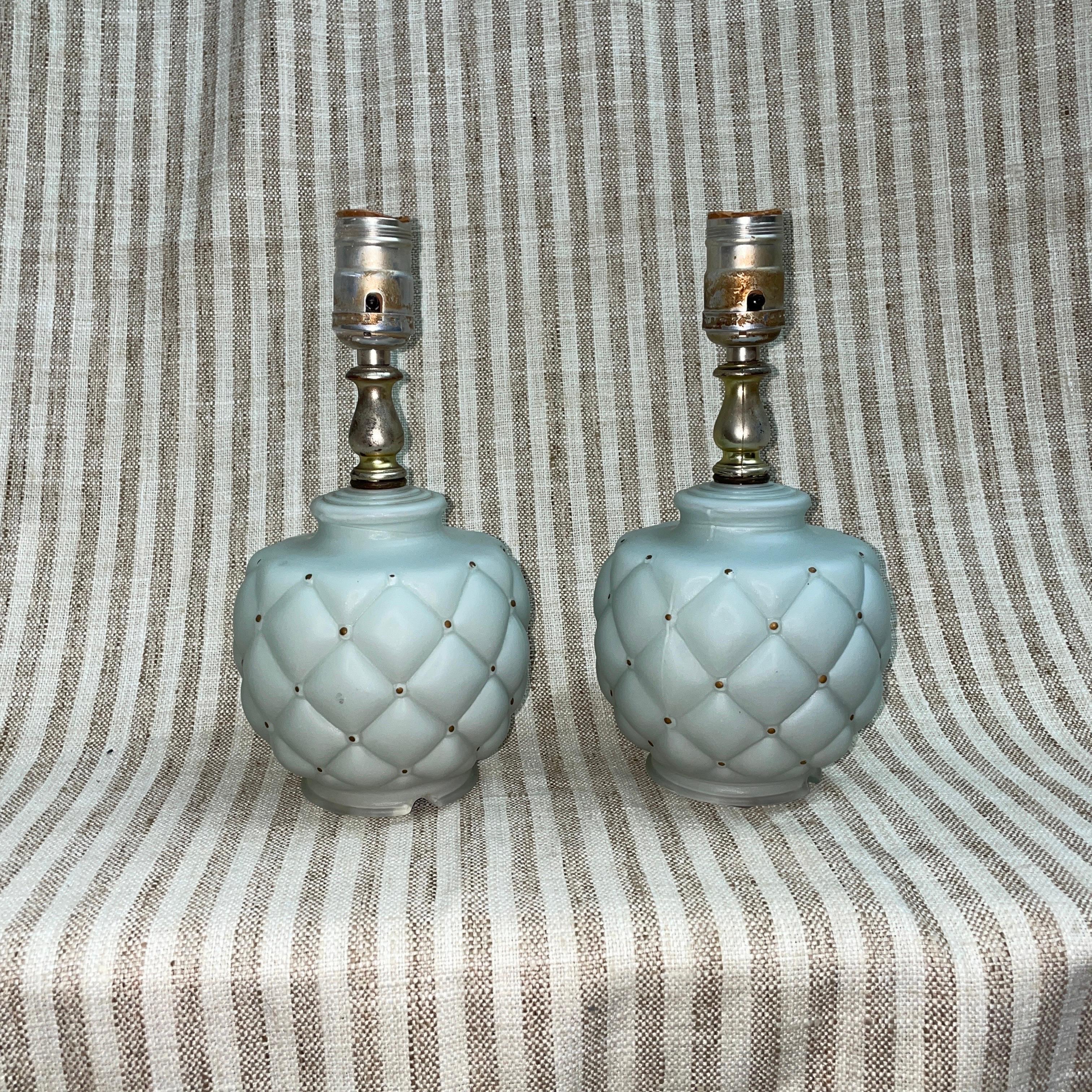 A pair of blue glass table lamps that would be perfect for a small table or nightstand. The lamps are baby blue with a gold paint dotted along the quilt-like surface. Unmarked. Original cord which is still in good shape. Both lamps work perfectly.