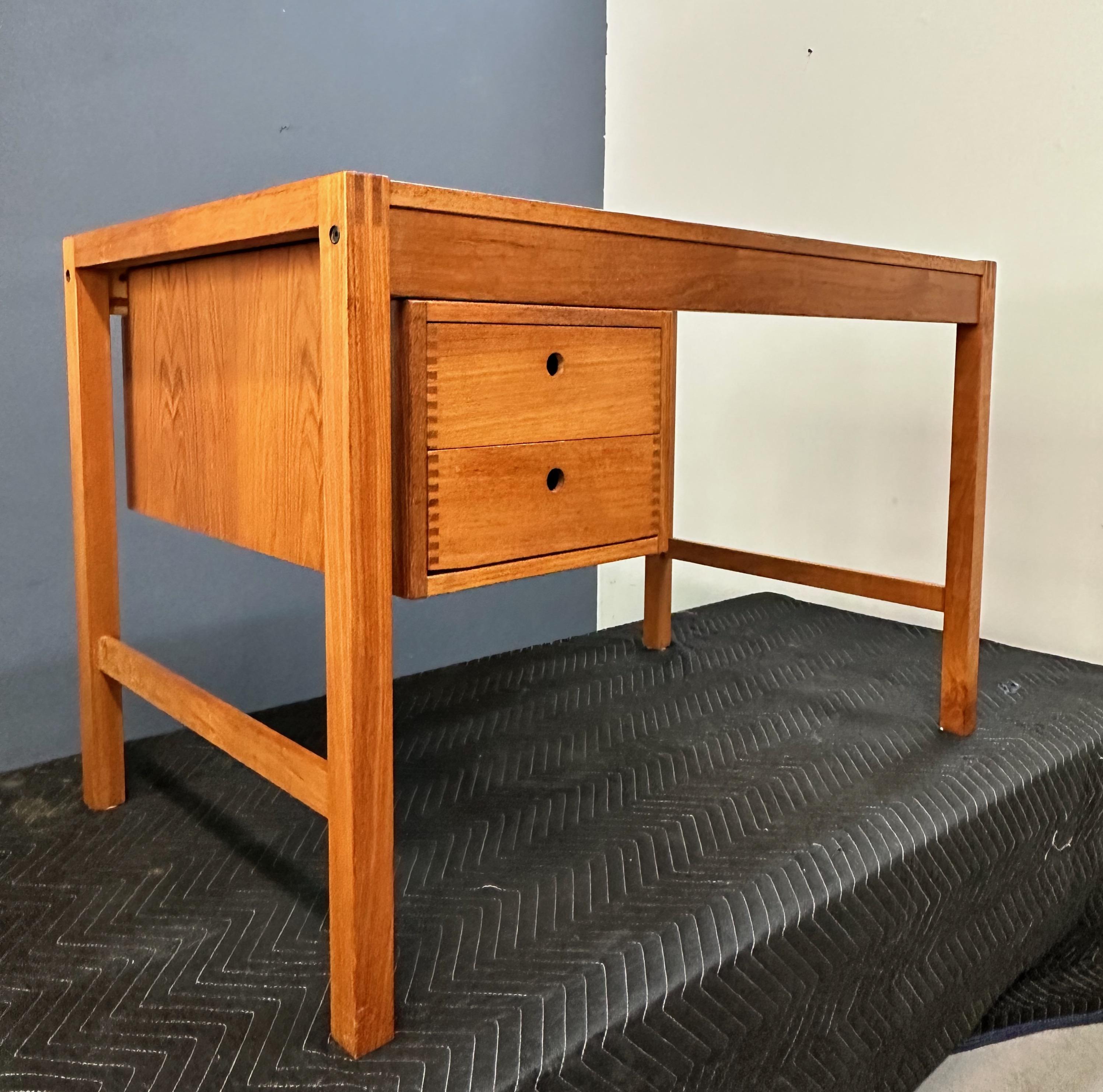 This vintage Danish desk is constructed of beautiful durable teak with visible box joints on drawers and desk corners.  One unique feature of note is the slide mounted drawer section which can move easily to any position along the length of the