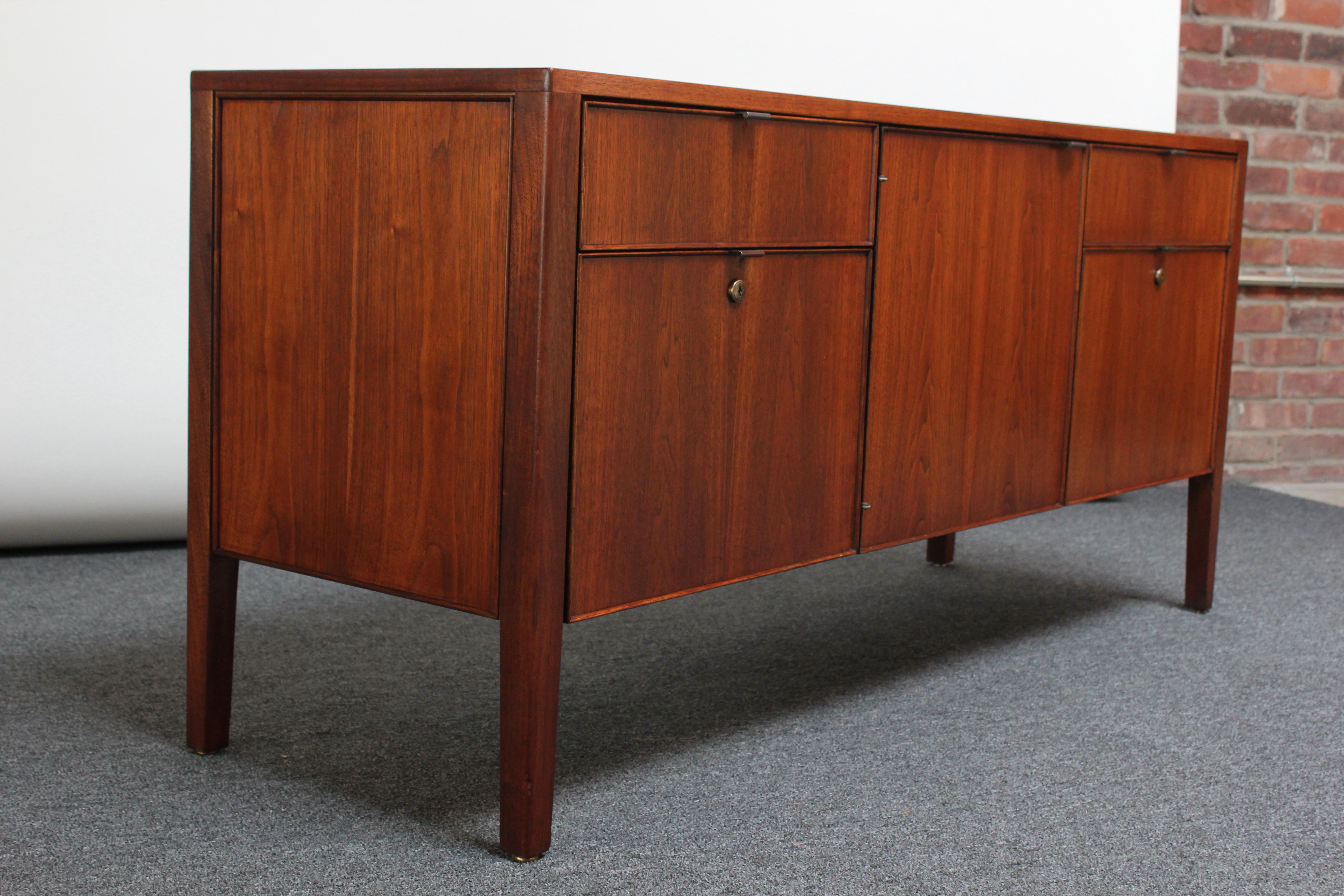 Diminutive American Modern walnut credenza By Stow Davis featuring an open storage compartment with a metal 