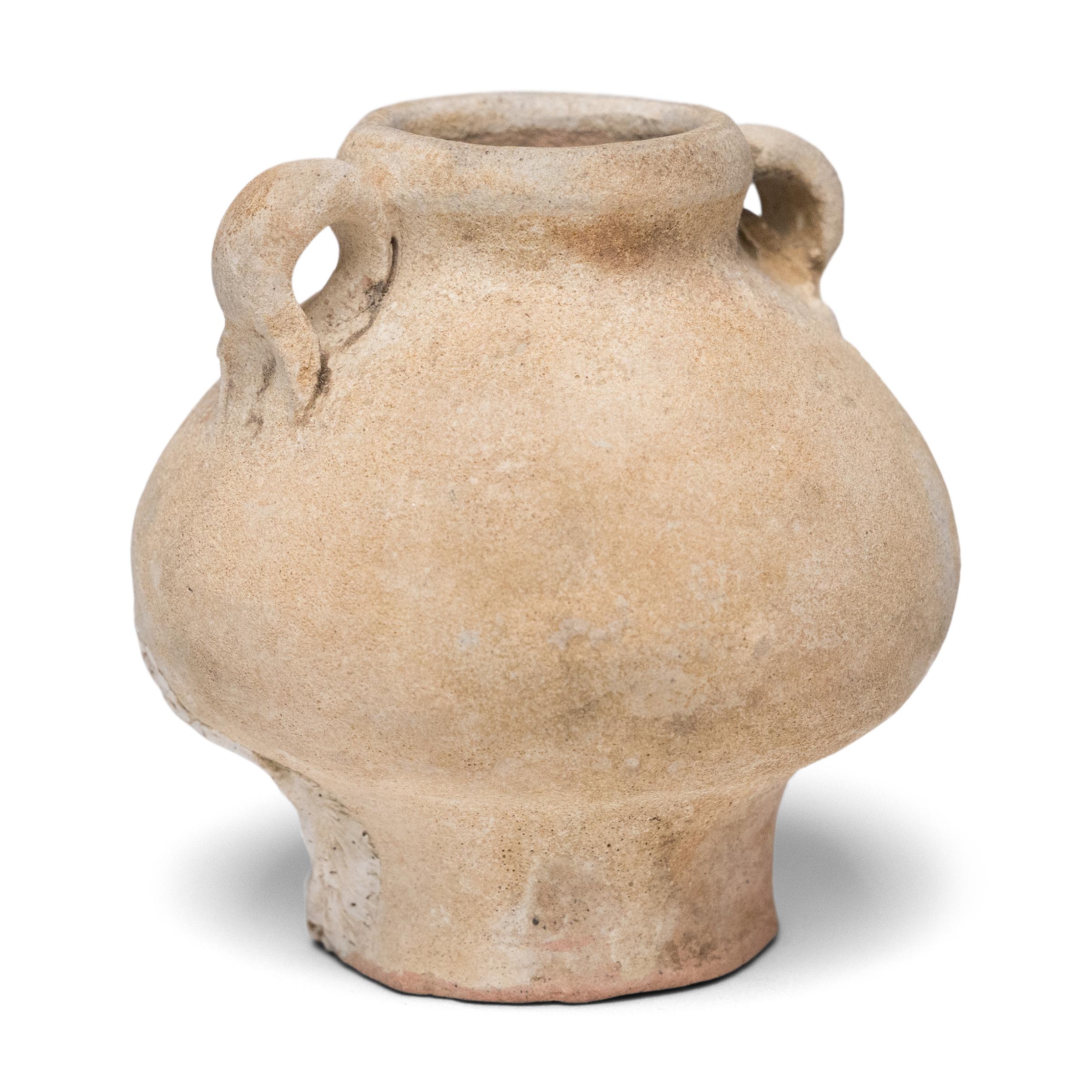 Die erodierte Oberfläche dieses zierlichen Medizinbehälters aus der Ming-Dynastie erzählt eine Geschichte von Handel, Tradition und verlorenen Schätzen. Die poröse, matte Oberflächenstruktur deutet darauf hin, dass das Gefäß viele Jahre im