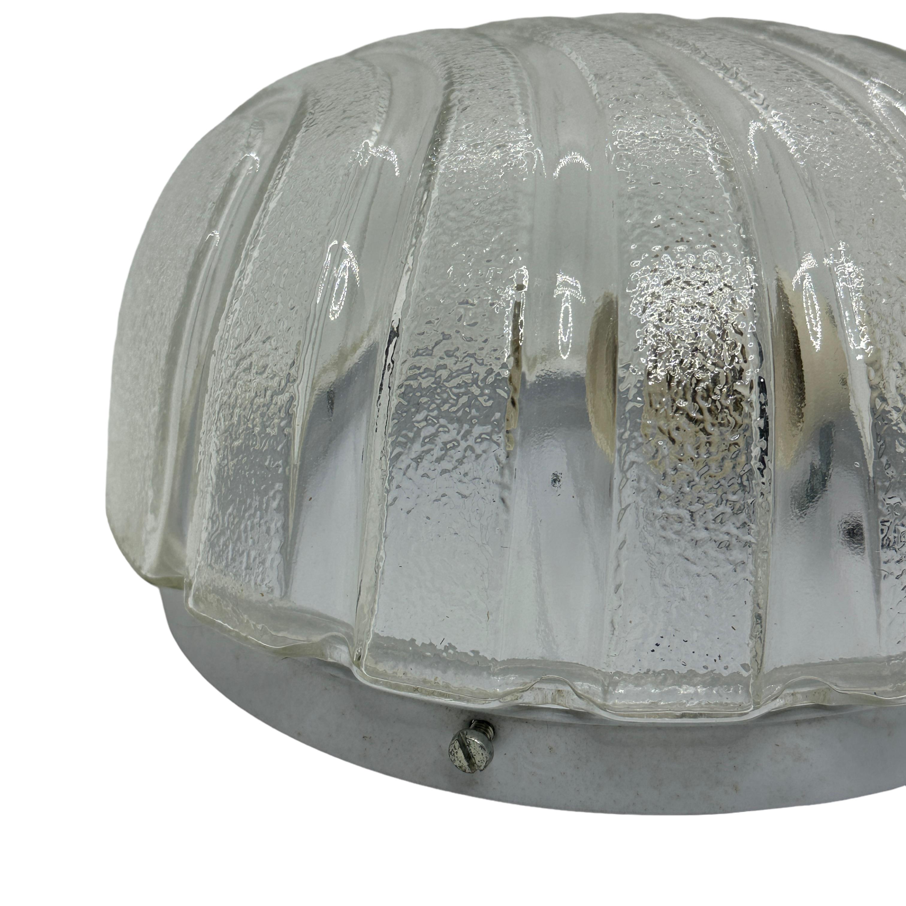 A petite gorgeous futuristic glass flush mount. It can be used also as a sconce. The light fixture requires one European E27 bulb, up to 60 watts. Clear ice glass, mounted on a white lacquered base. A nice addition to any room.