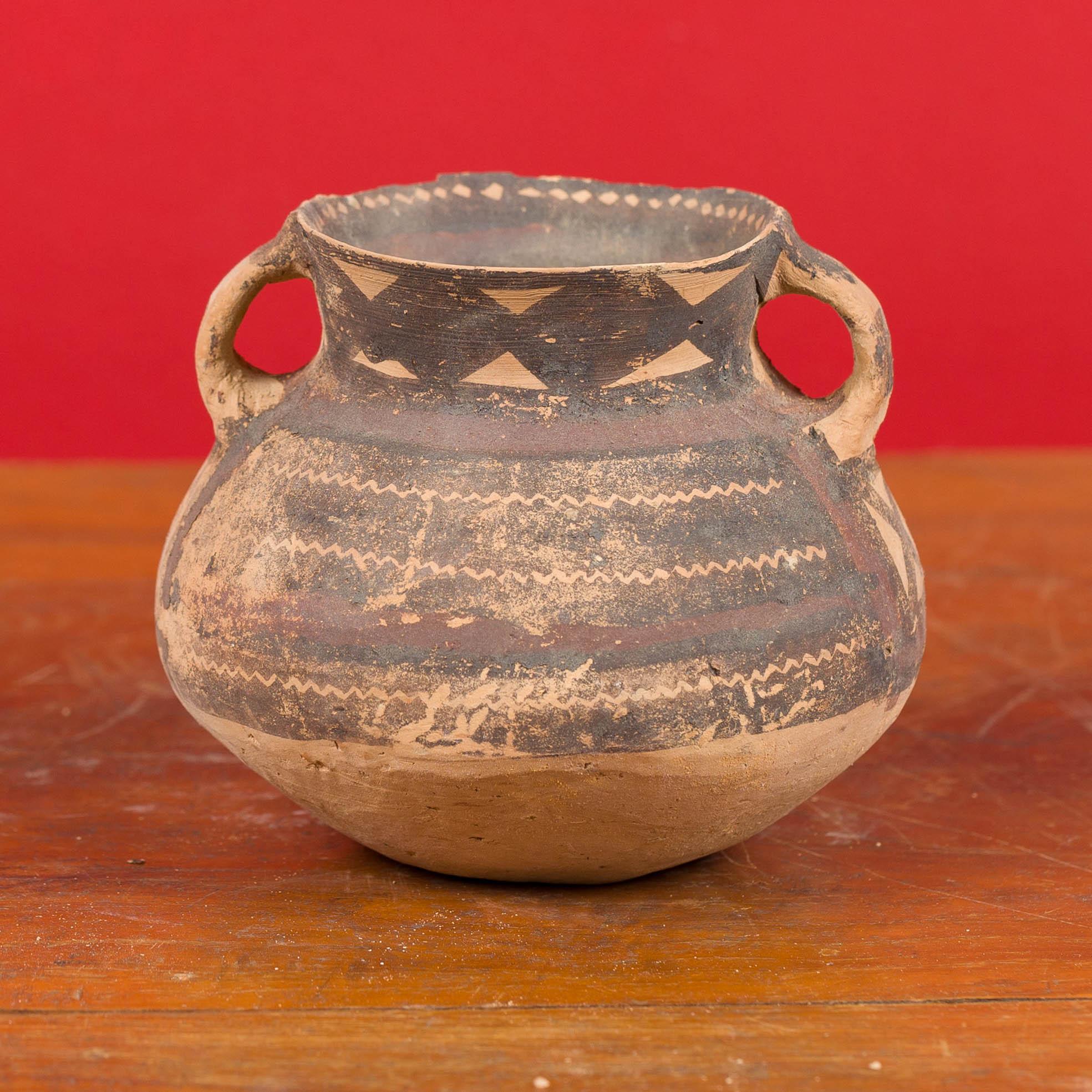 A Neolithic Chinese terracotta pottery from 4000-3000 BC, with lateral handles and brown painted geometric décor. Born in China during the Neolithic period, this pitcher attracts our attention with its nice patina, simple lines and geometric motifs.