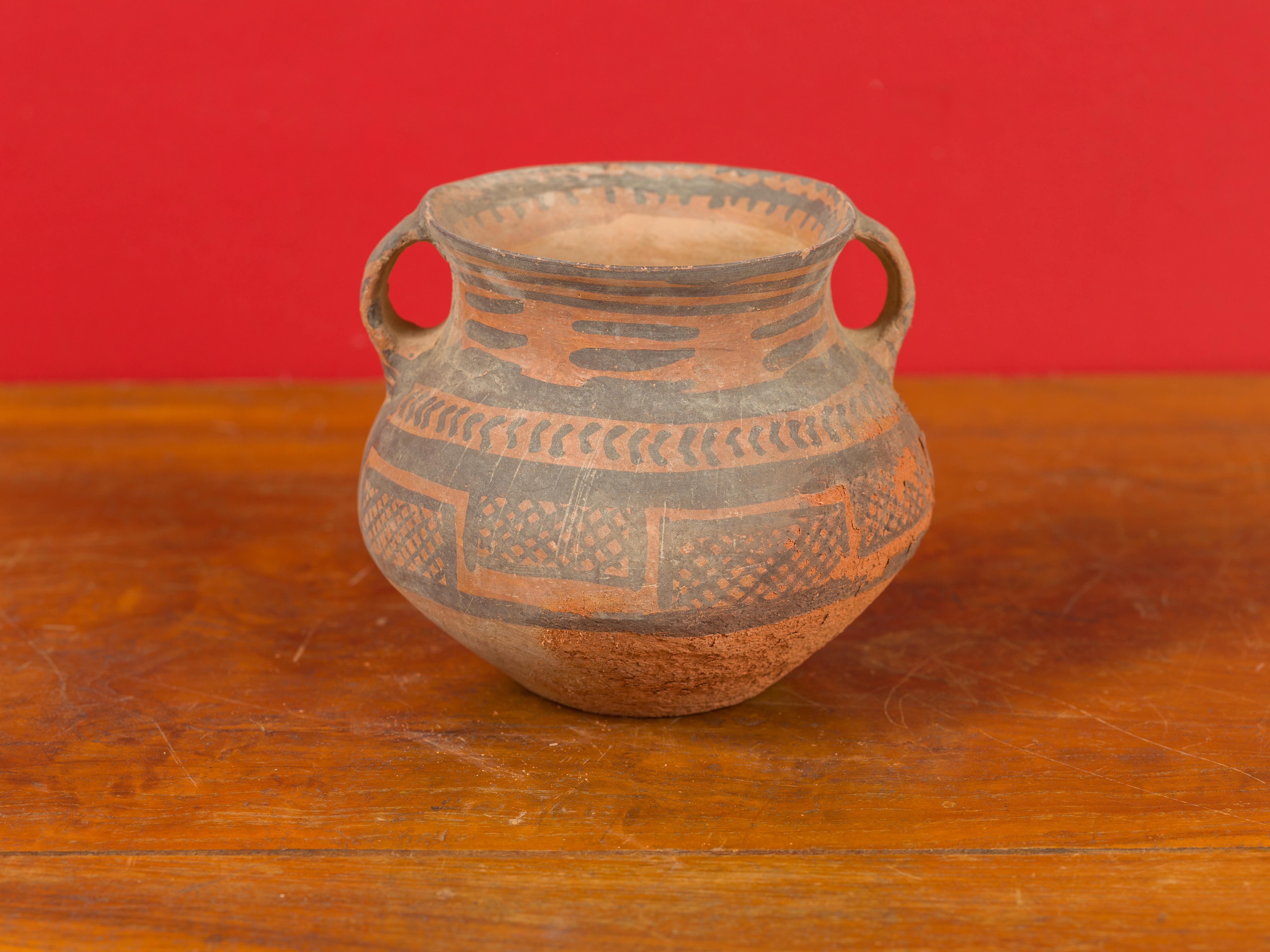 A Neolithic Chinese terracotta pottery from 4000-3000 BC, with lateral handles and brown painted geometric decor. Born in China during the Neolithic period, this pitcher attracts our attention with its nice patina, simple lines and geometric motifs.