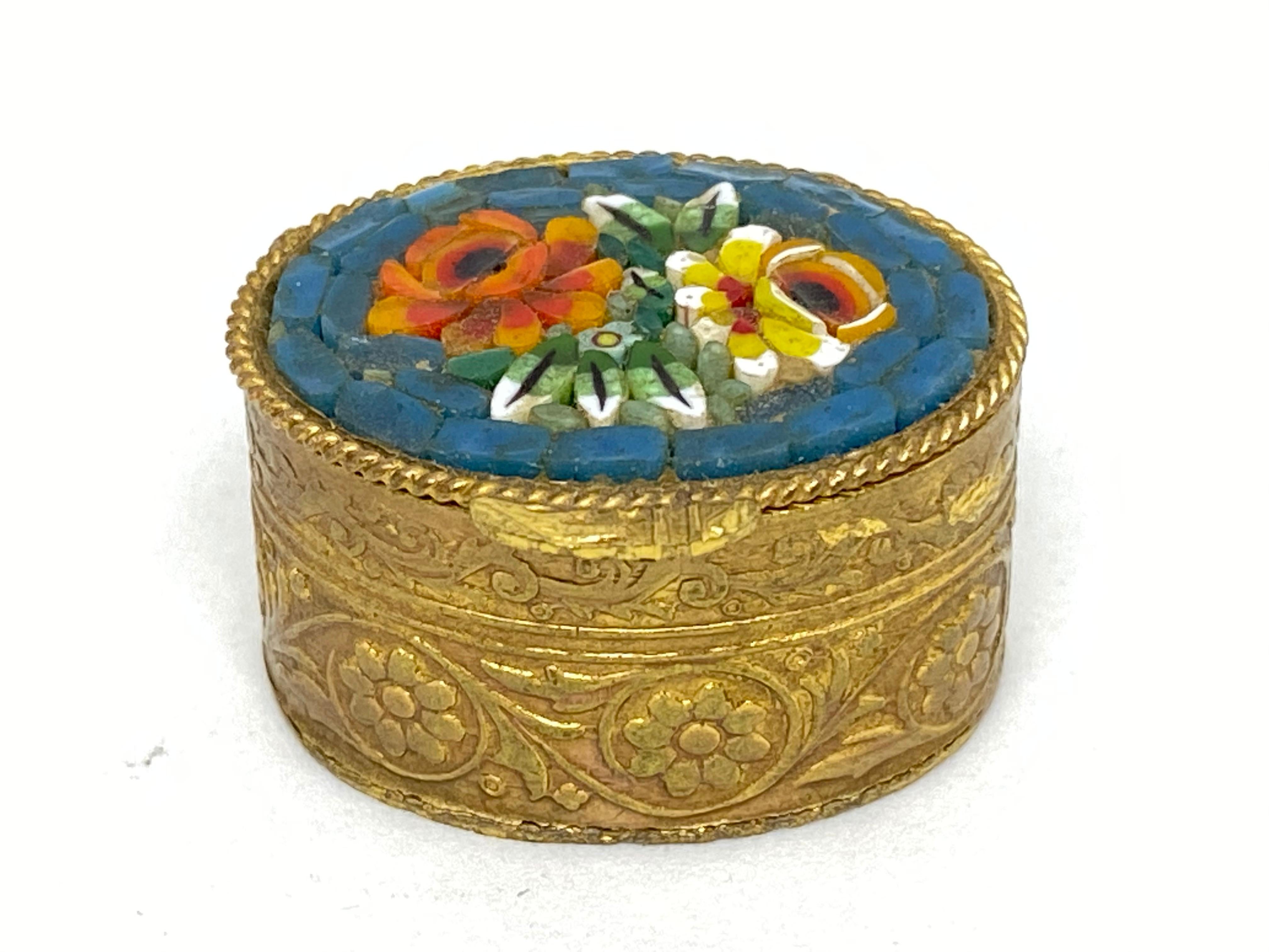 A gorgeous petite micro mosaic pill box. The top featuring micro mosaic made flowers. No restoration has been carried out on this charming little box, which remains in very stabile and functioning condition, wear is consistent with its age and use.