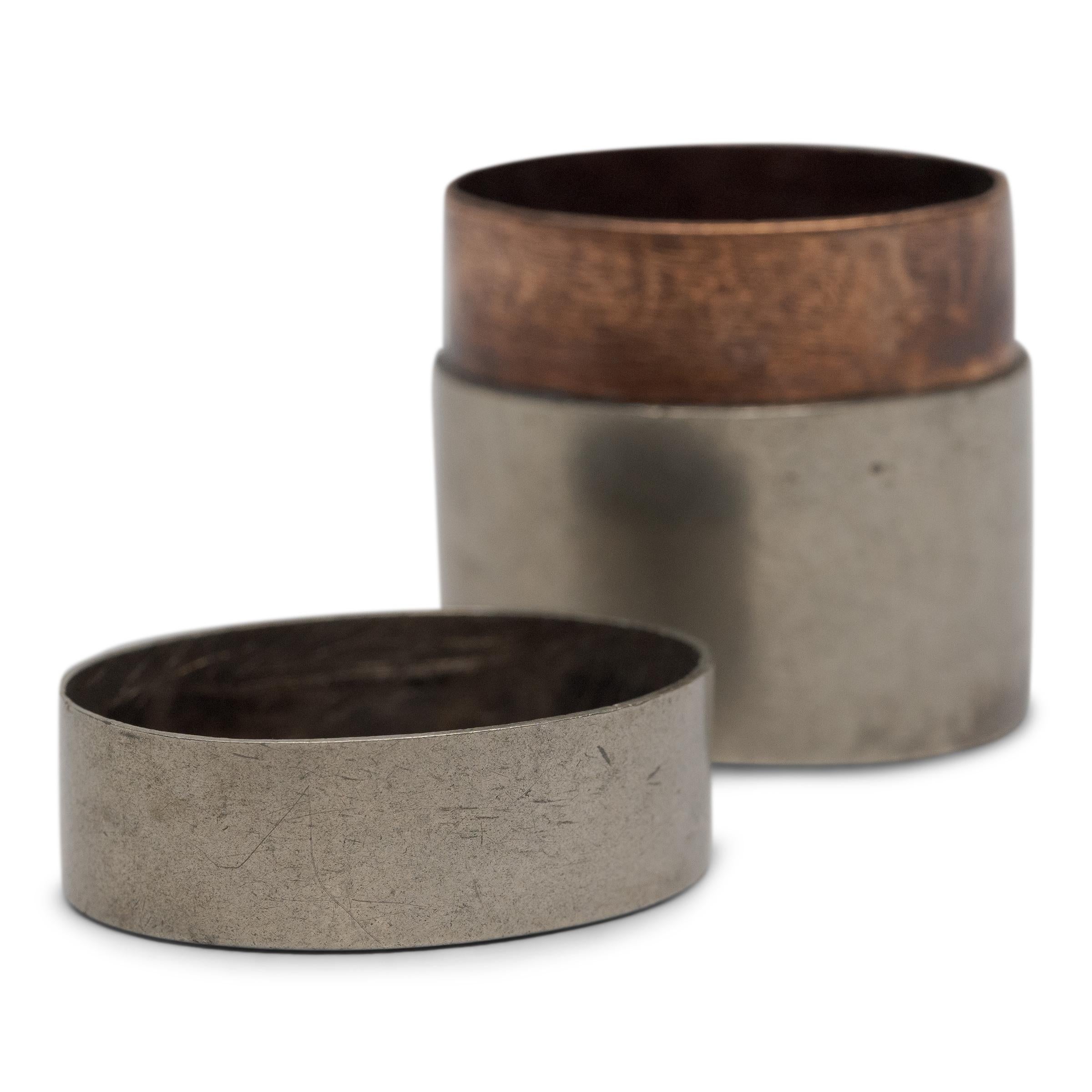 A petite 19th-century canister once used to store a smoker's personal supply of opium paste. Perfecting line and form, the small box has a balanced, oval form shaped of white brass (baitong) with a copper interior lining.