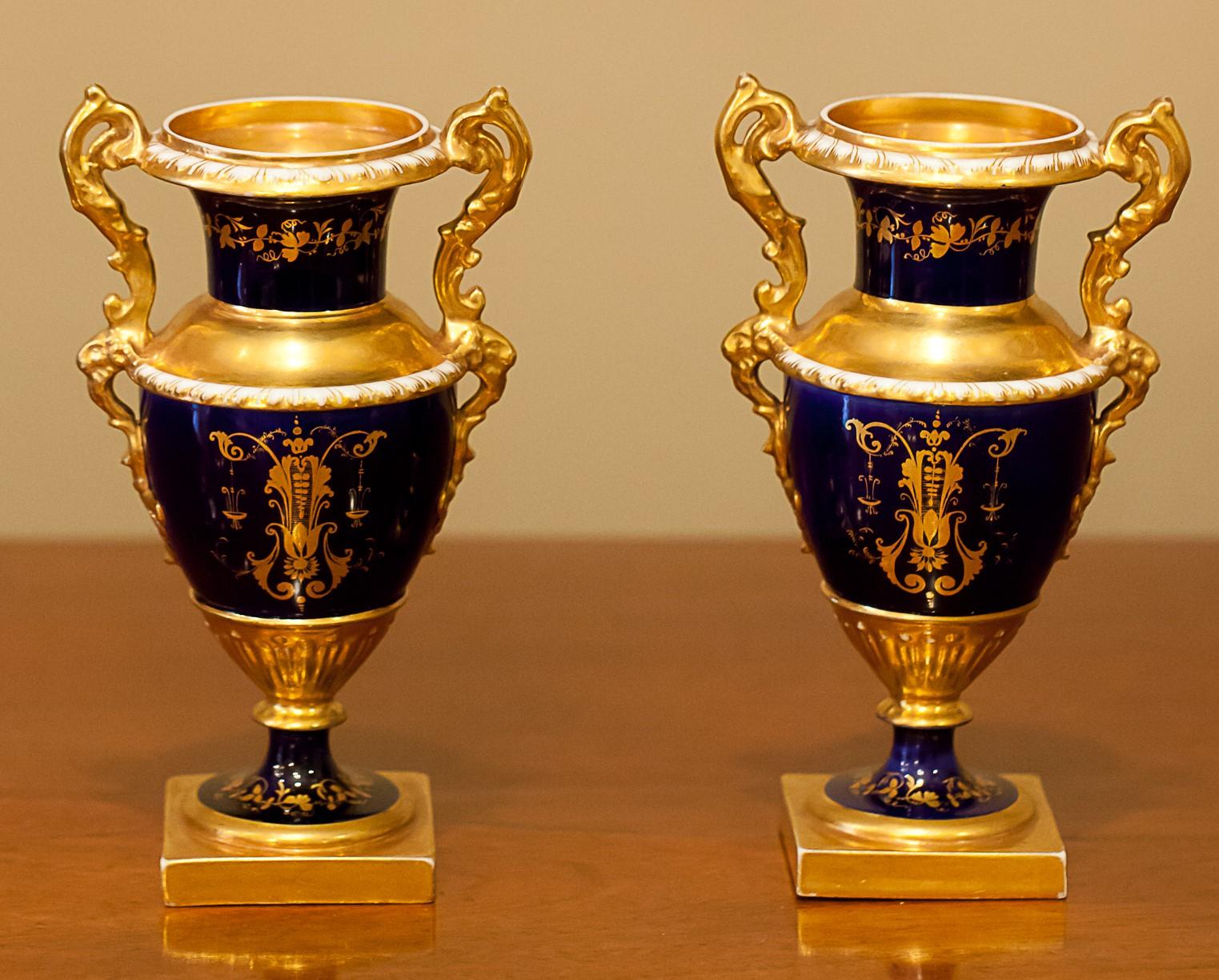 These beautiful Ovid form vases, while unmarked, appear to the work of the Derby factory possibly Barr, Flight and Barr. They have floral panels on one side and a gold leaf design on a cobalt ground on the other. They possibly were originally part
