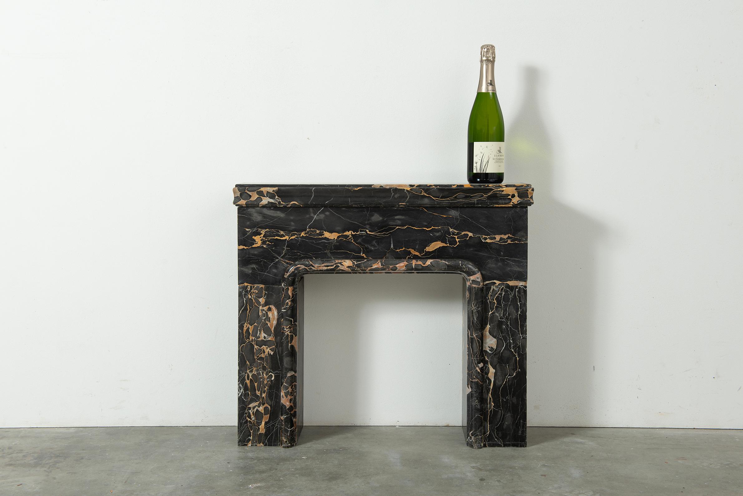 Truly unique Petite Portoro Fireplace, delicious bottle of Cremant is sadly not included...

This lovely petite mantel came from a countertop in the south of Amsterdam, Holland.
Its thick and subtle profiled top rests on a simple and plain frieze