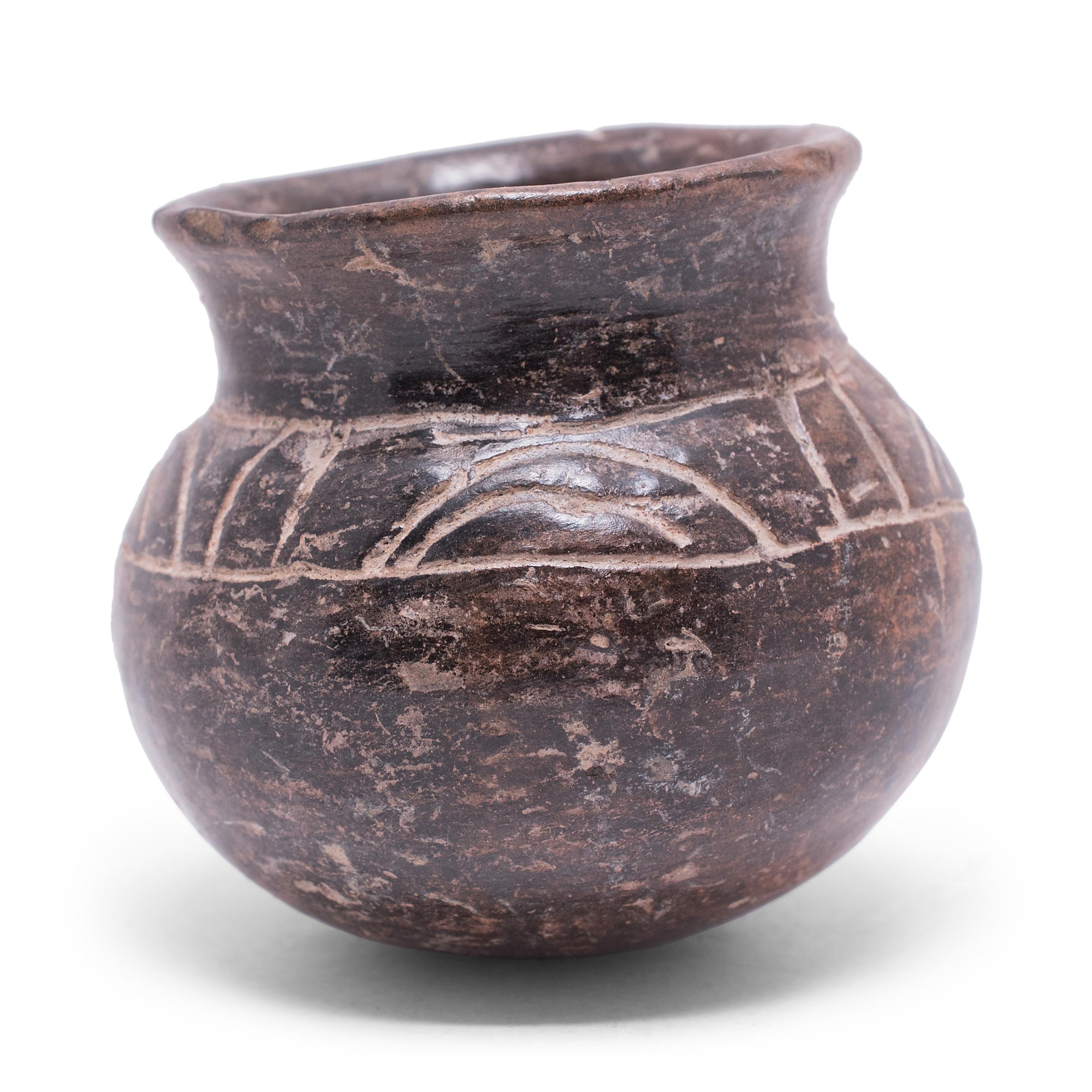 Exhibiting a rich patina, this petite blackware vessel shows many telltale signs of Pre-Columbian pottery. Speckled with imperfections, the vessel's darkened surface was achieved by applying a mineral-rich slip for a monochrome finish that