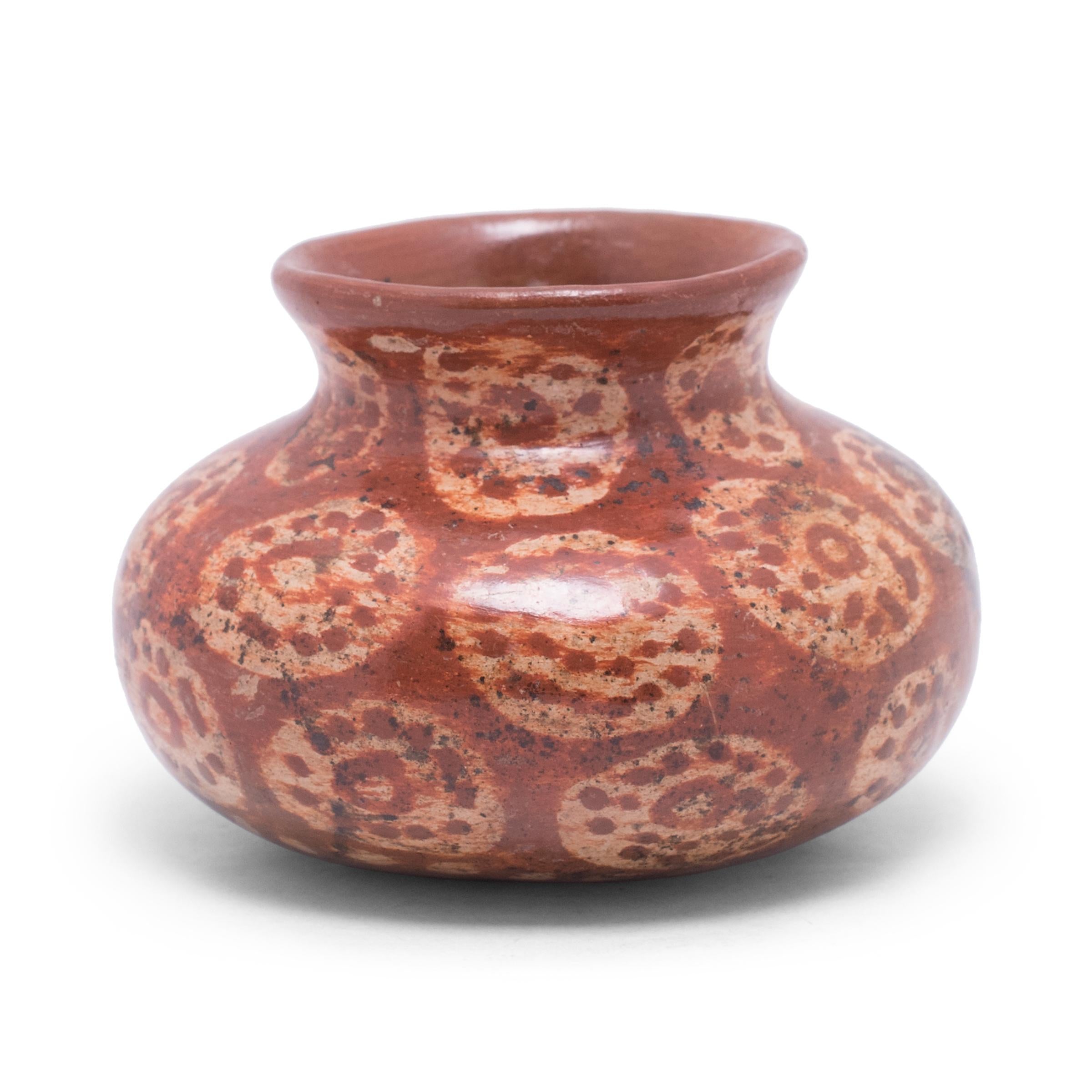 This little jar is a beautiful example of Mesoamerican pottery, decorated with red and white slip clay in the style of Chupícuaro ware. The olla vessel has a wide, globular body with a rounded base, constricted neck, and flared lip. The exterior is