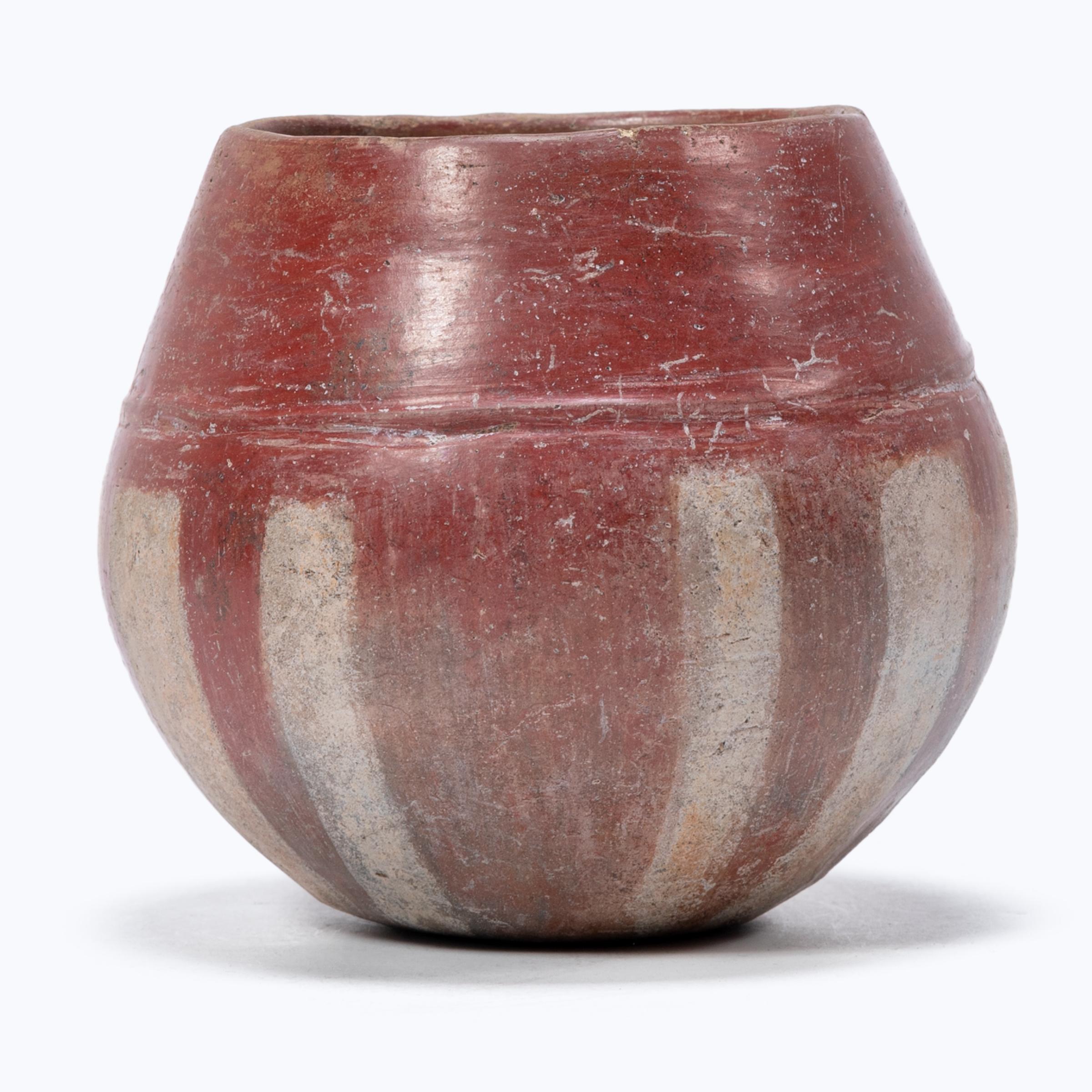 This petite ceramic vessel was made by an artisan of the Chupícuaro culture, which was settled in Guanajuanto, Mexico from 500 BC-300 AD. Exhibiting a rich patina, the bowl's surface is painted in a striped pattern with slips of buff and red clay.