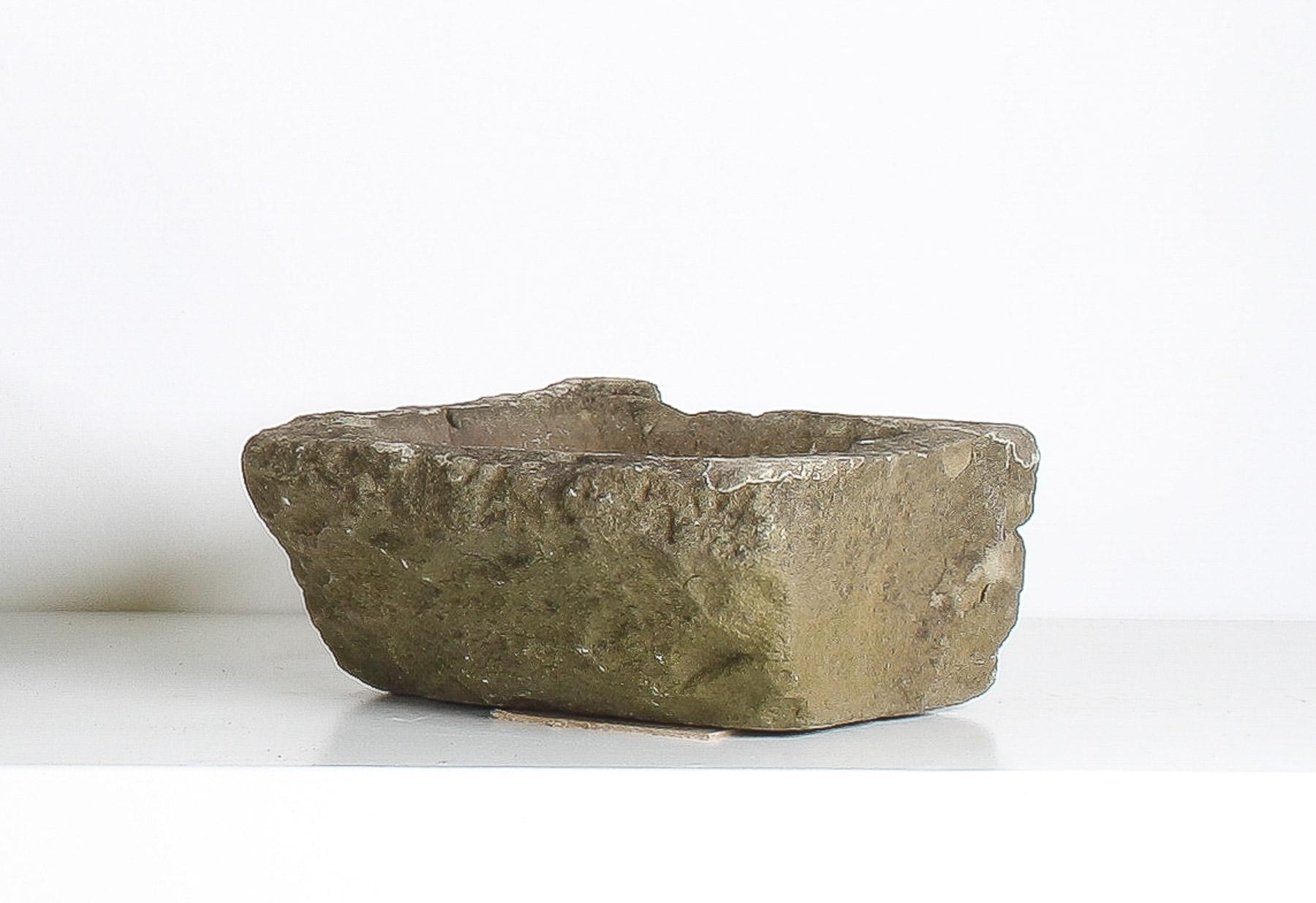 Embrassez la beauté de l'imperfection avec cette petite, mais parfaitement formée, jardinière en pierre sculptée. Cette pièce primitive, datant probablement du début des années 1800, est sculptée à la main dans de la pierre naturelle, créée par les