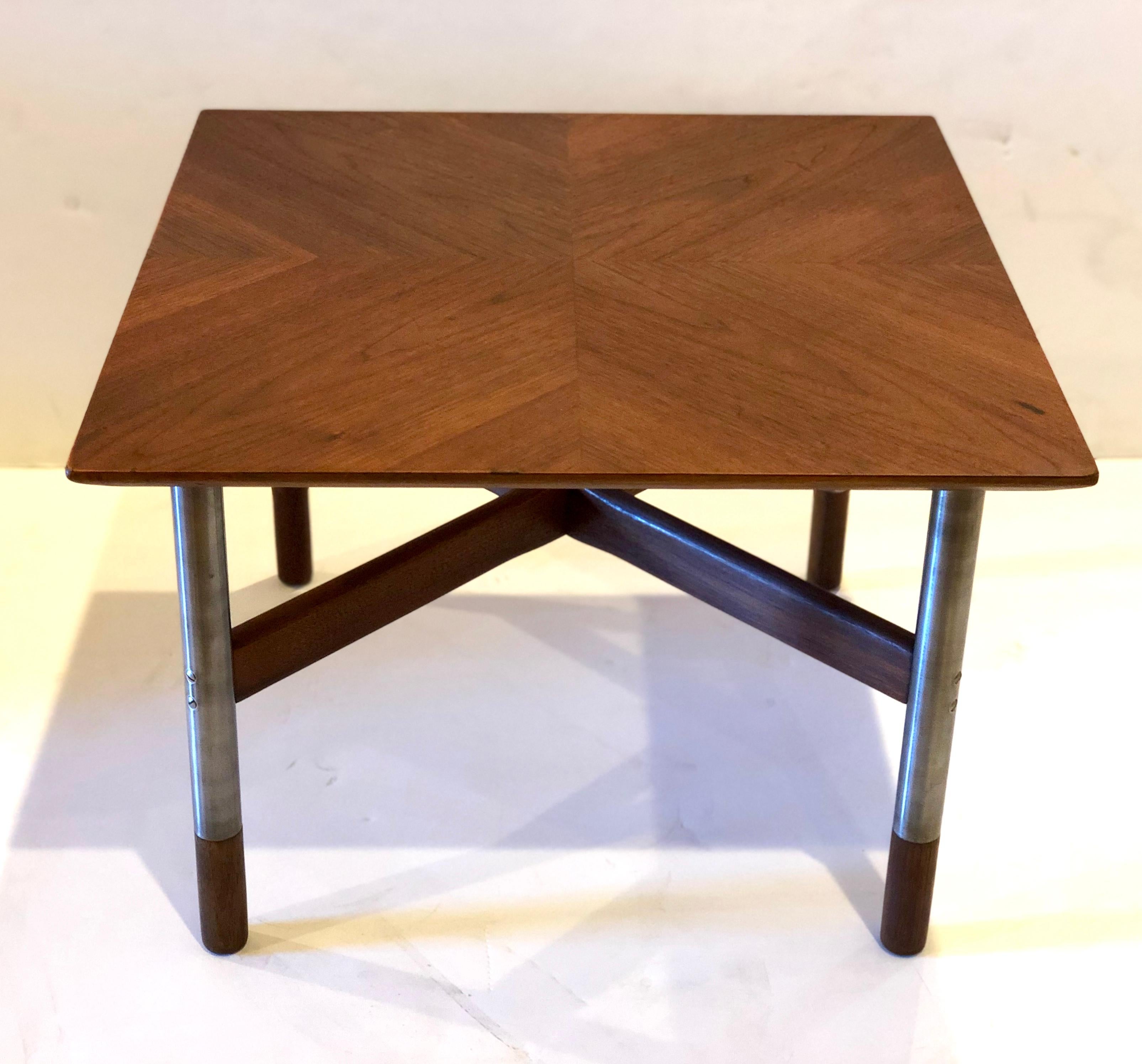 Beautiful and rare small square table with inlaid design top, beveled edge and crossbar base, stainless steel legs with teak tips, very similar to Finn Juhl designs.