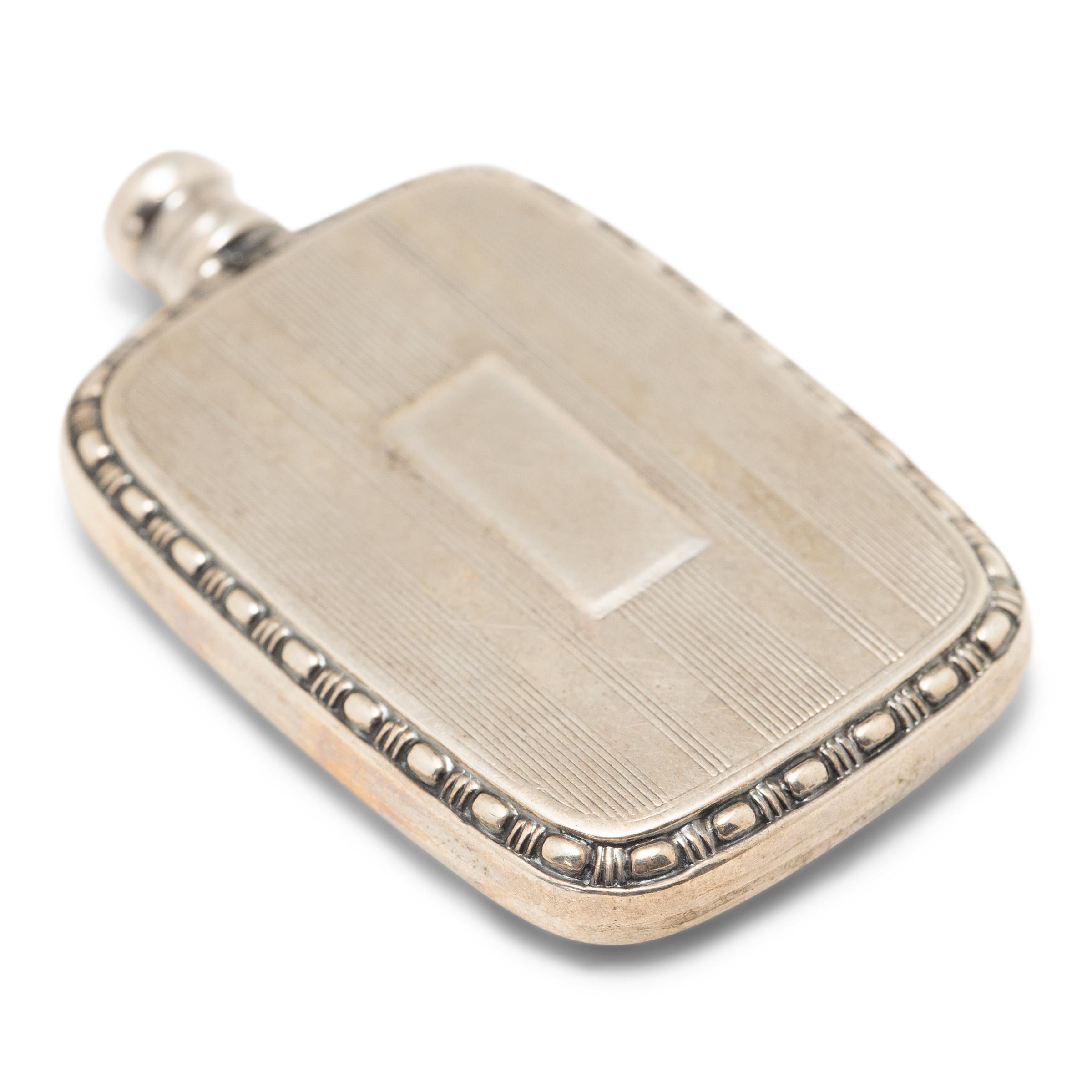 This petite silver perfume bottle from early 20th century once kept a lady's fragrance close to hand, perfectly sized to tuck into a pocket or evening bag. The small bottle is shaped from sterling silver to a flattened, rectangular form and features
