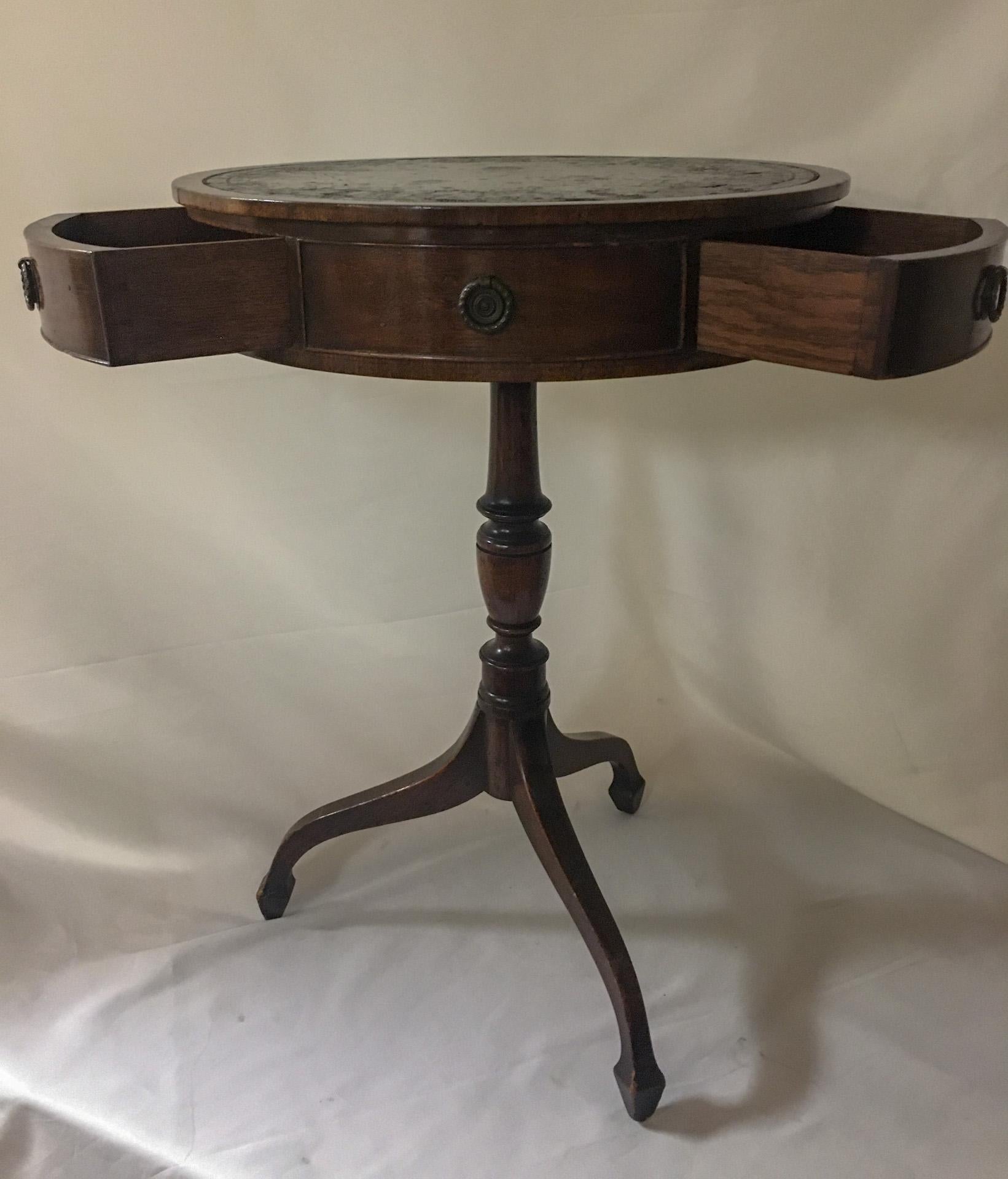 This petite size Regency style drum, sometimes called a rent table, features three fitted drawers and three faux drawers, all with the original brass pulls. It revolves on a graceful turned stem and tripod base. 
