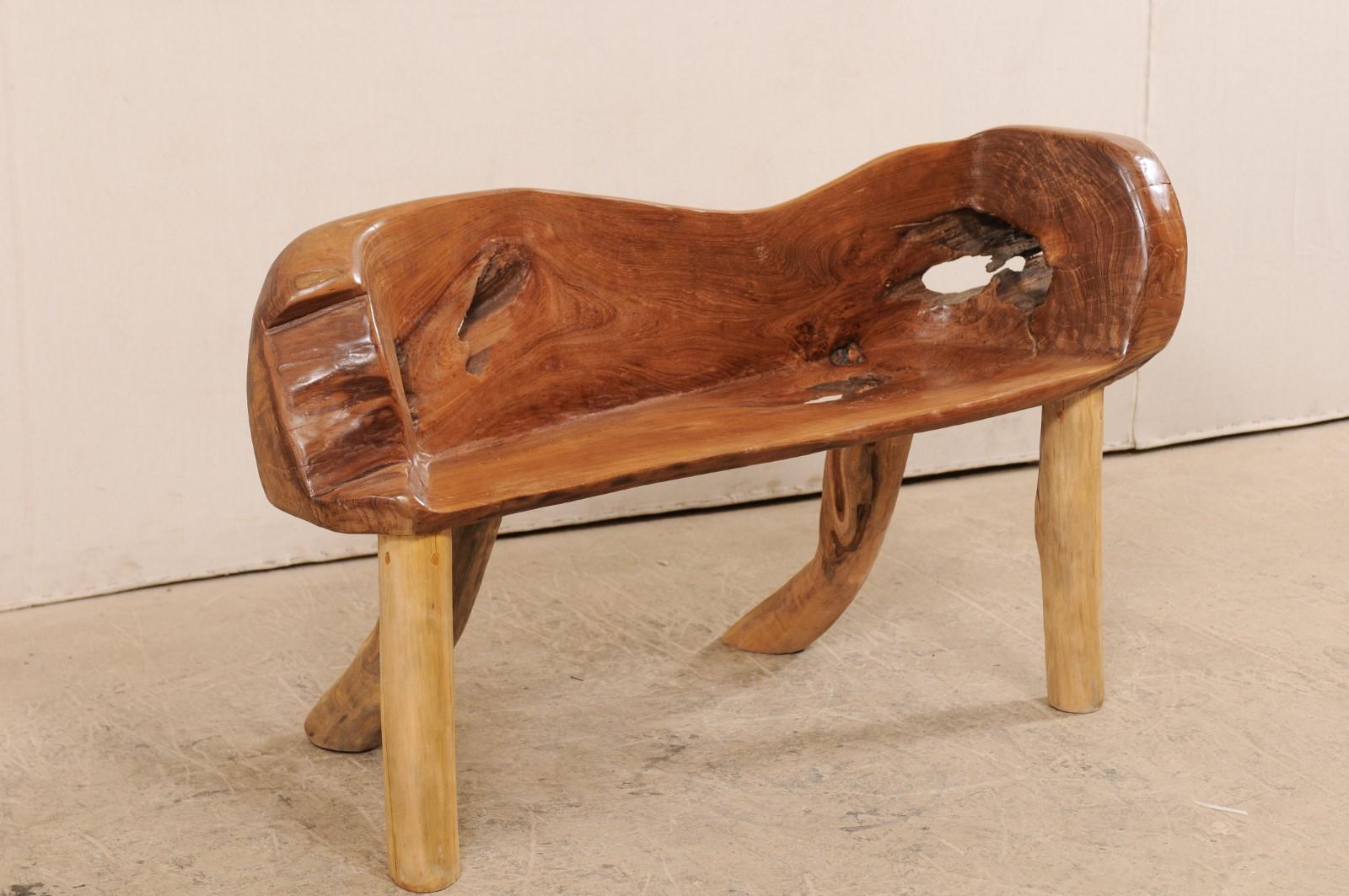 A natural teak wood bench with live edges. This cute little bench, just over four feet in length, has been created from the root and limbs of Indonesian teak wood, which has been smoothed and polished. Teak is a tropical hardwood which is