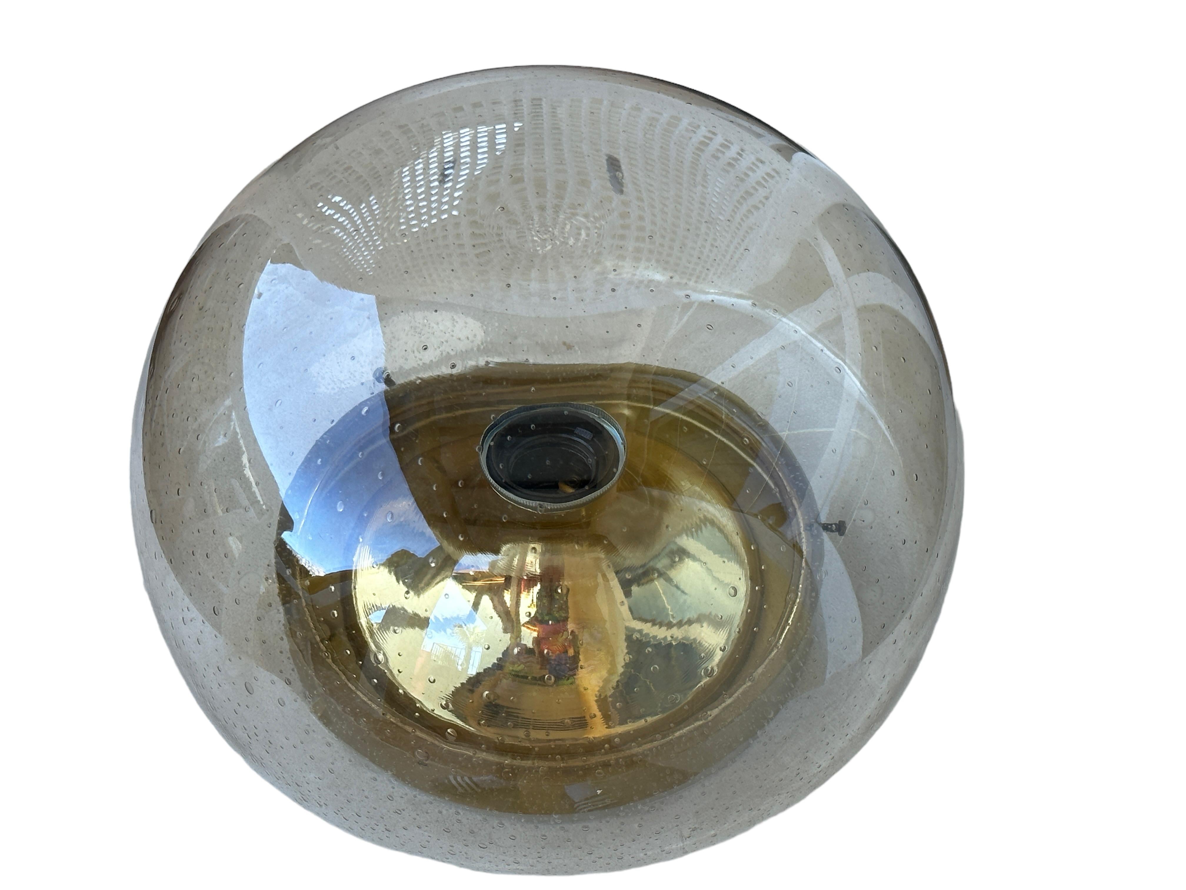 A beautiful flush mount by German manufacturer Glashuette Limburg. The bubble glass element is supported by a polished brass plate with a one light source. Beautiful bubble glass on a metal fixture. The Fixture requires one European E27 / 110 Volt