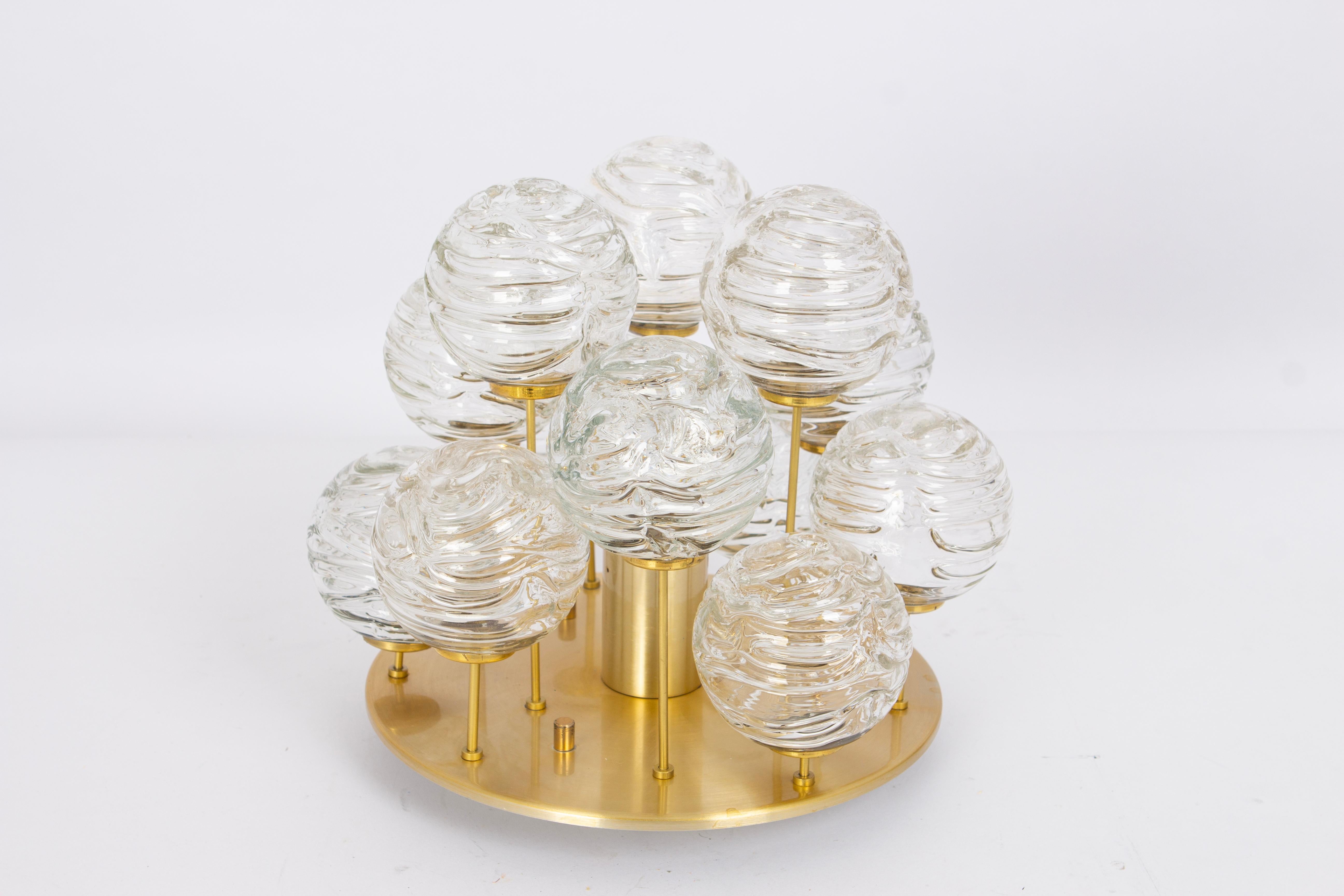 A Petite midcentury flush mount light made by Doria Leuchtern, manufactured in Germany, circa 1970-1979.

The flushmount is composed of many Glass swirl textured ice glass elements (snowballs) attached to a brass frame.
Made by Doria in Germany,