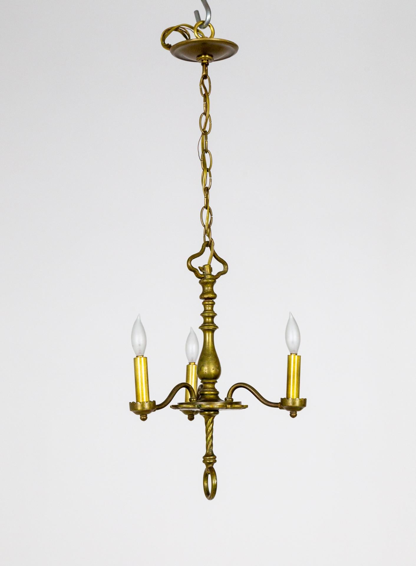 A refined, well proportioned, 3-light, brass chandelier with sophisticated accents and hand made details - the scalloped body plate, a chain hook that mimics the arm curvature, rope stem, turned body, loop finial and brass candle covers. Late 19th
