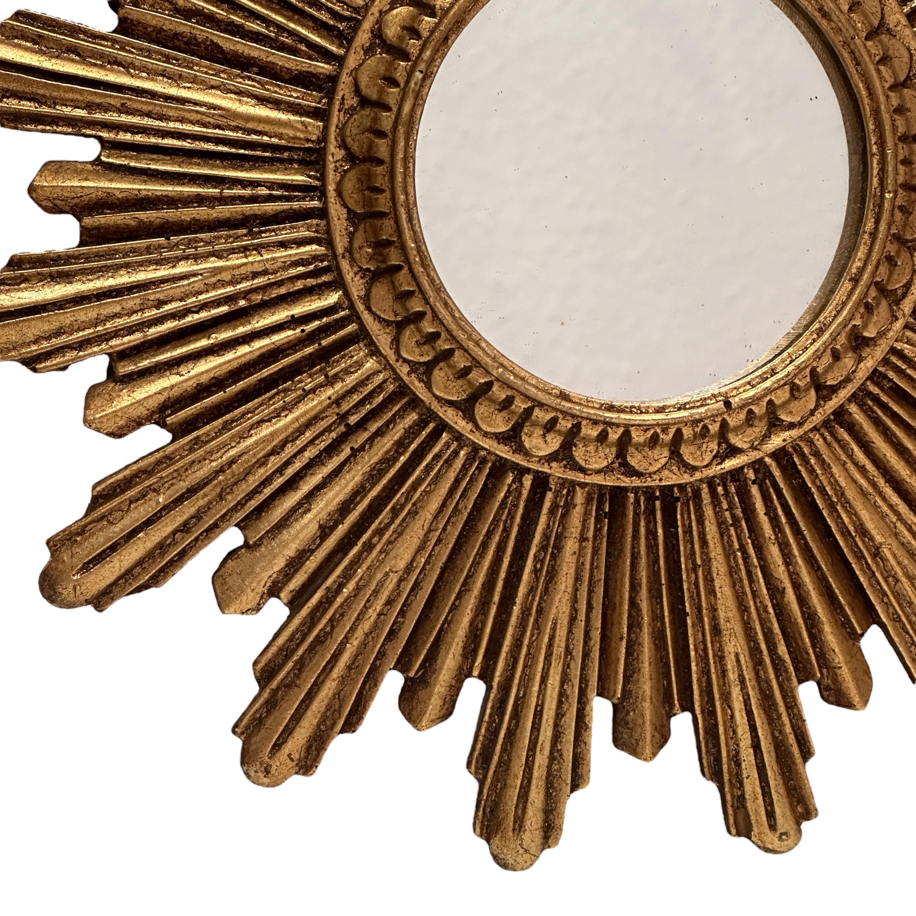 A petite starburst sunburst mirror. Made of gilded resin. It measures approximate 10.5