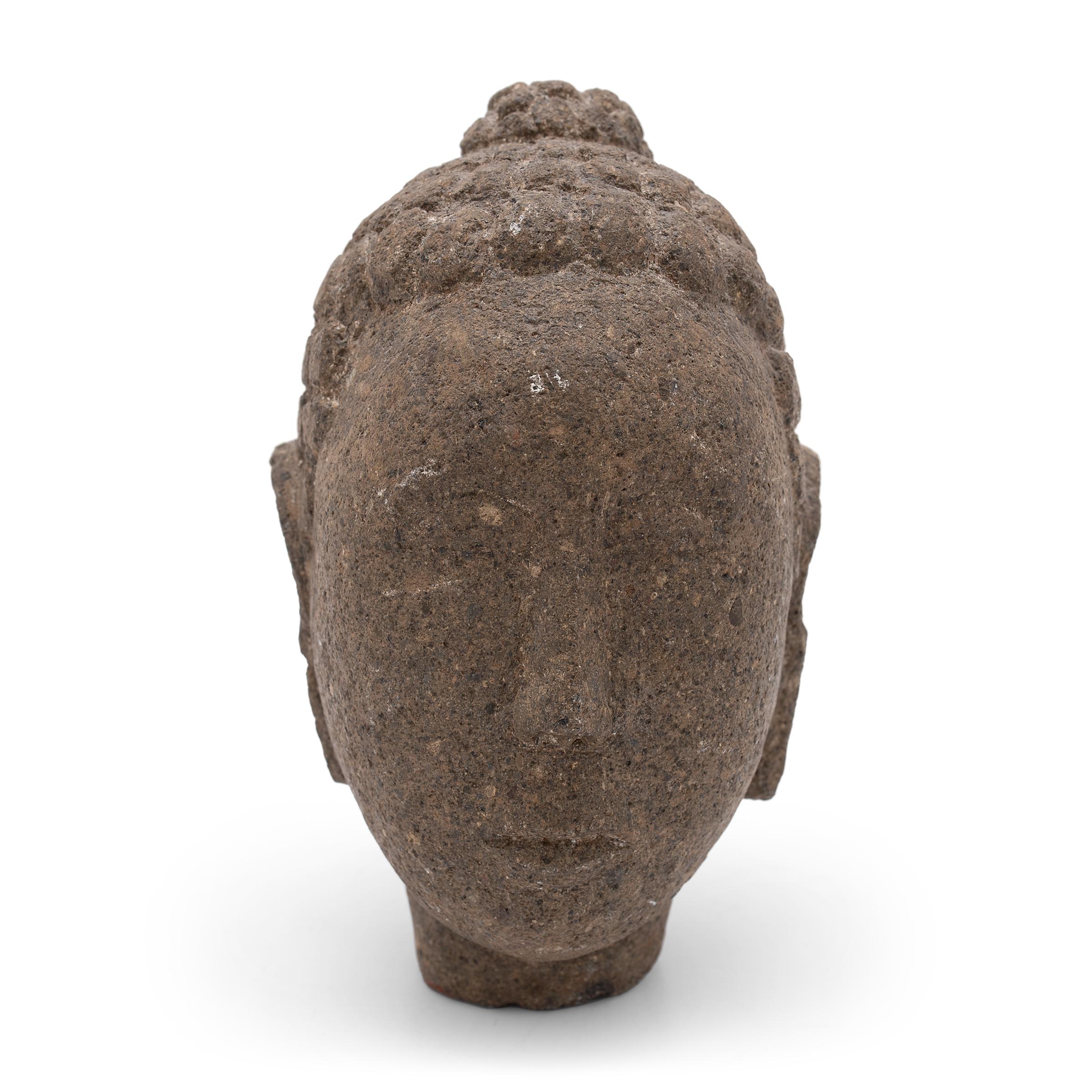 With closed eyes and a gentle expression, this petite stone Buddha head brings calm and serenity to its surroundings. The hand-carved figure depicts the historic Buddha Shakyamuni, also known as Shaka, Gautama Buddha, or Prince Siddhartha. Commonly