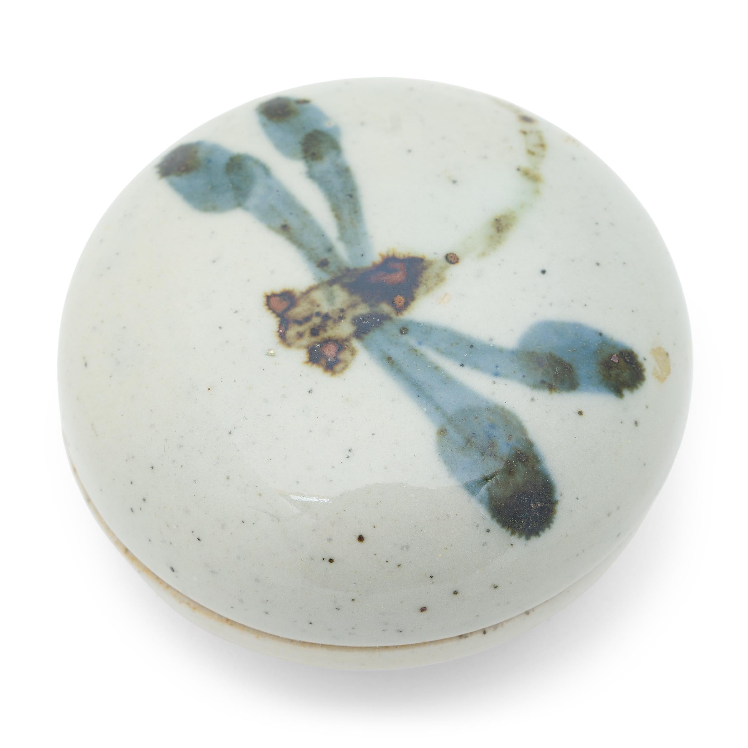 This petite stoneware box by a contemporary ceramicist is decorated with a flitting dragonfly, drawn with painterly brush strokes that reveal the maker's hand. A translucent grey-blue glaze cloaks the box inside and out for a glossy finish. Maker's