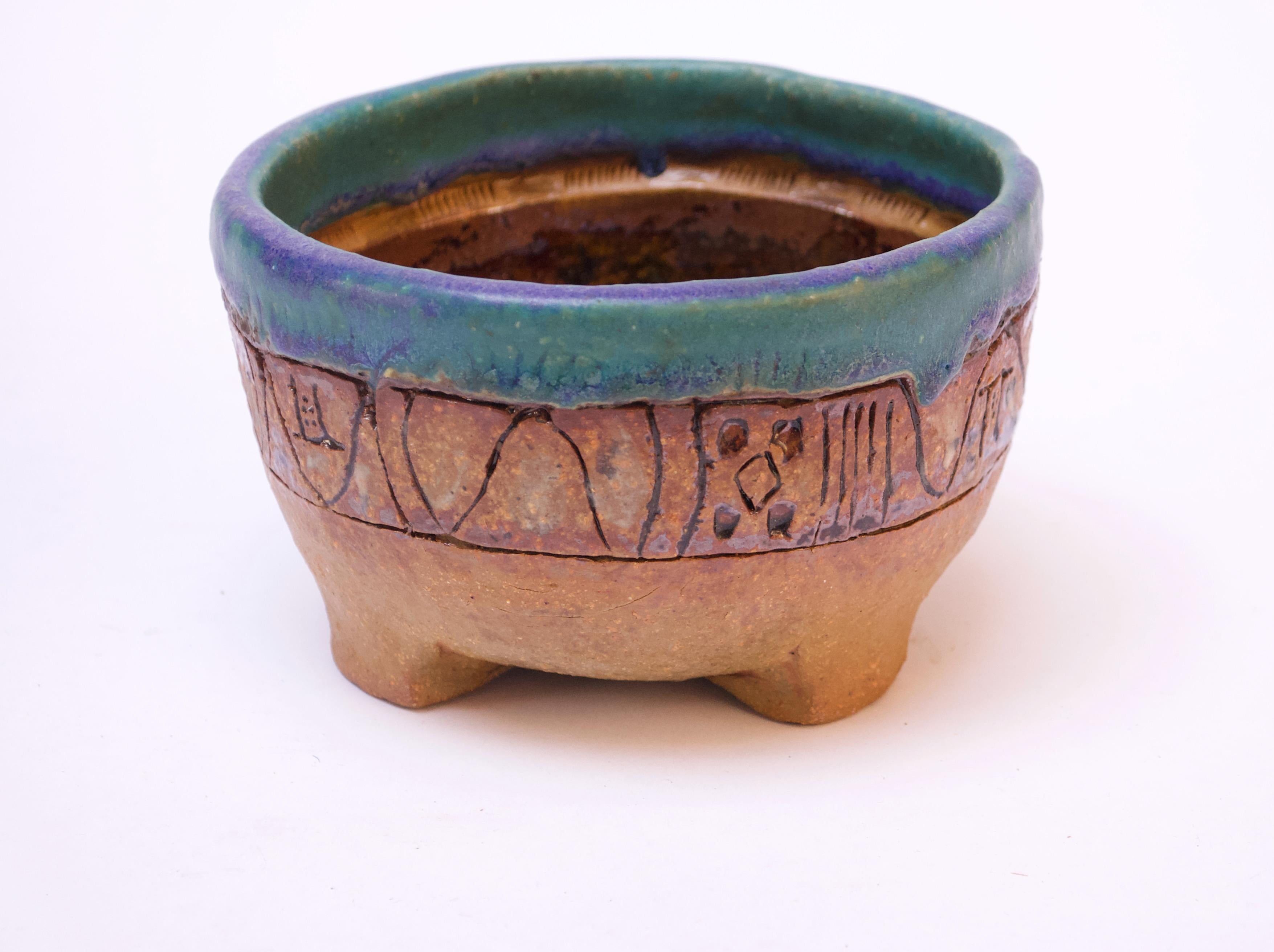 Heavily textured footed mortar / decorative bowl with sgraffito decoration throughout. The main color is ochre with an attractive top banding of blue and green. The interior design is a tree of life motif with three floral blooms composed largely of