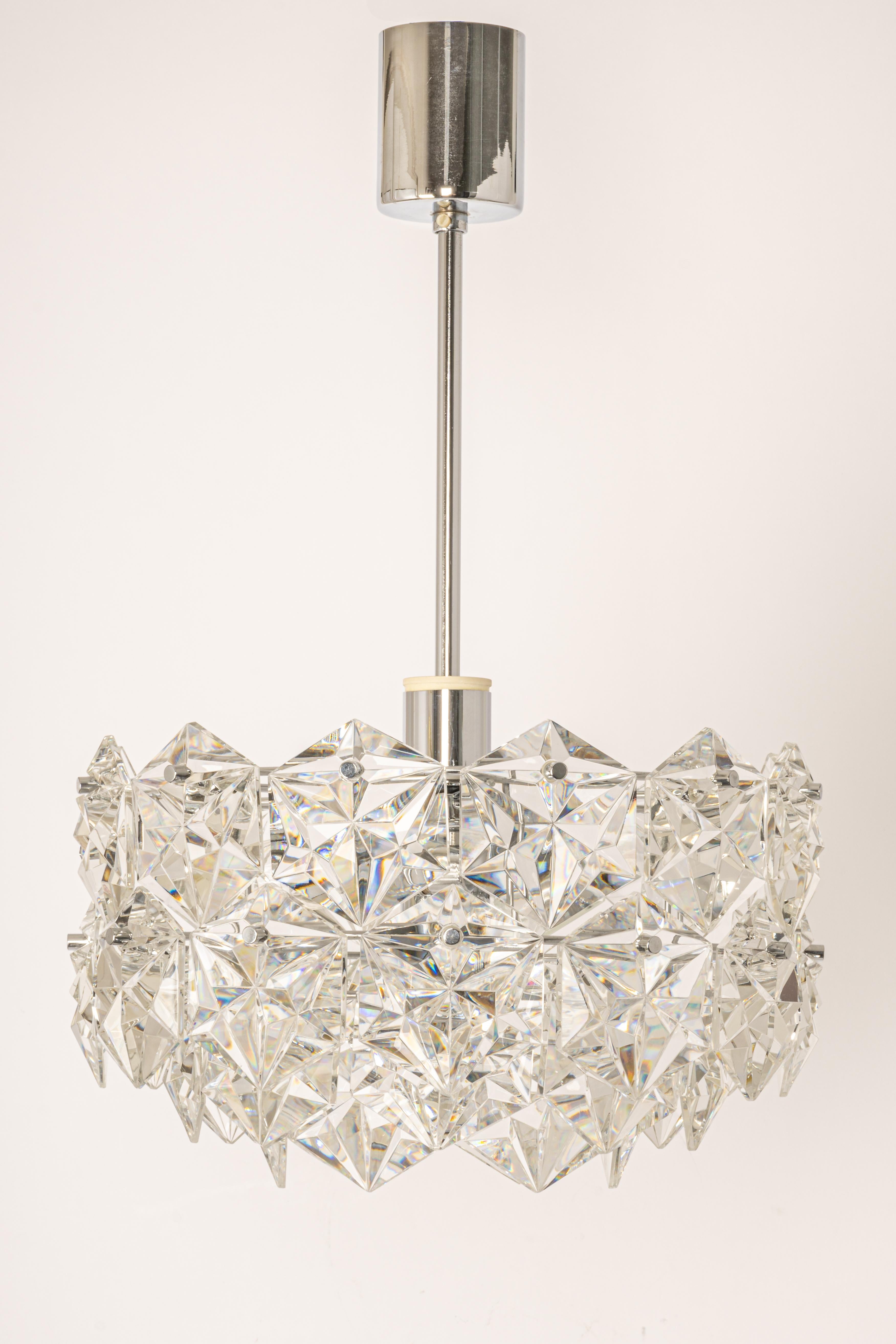 A stunning three-tier petite pendant light by Kinkeldey, Germany, manufactured in circa 1970-1979. A handmade and high quality piece. The ceiling fixture and the frame are made of chrome and have 3 rings with lots of facetted crystal glass