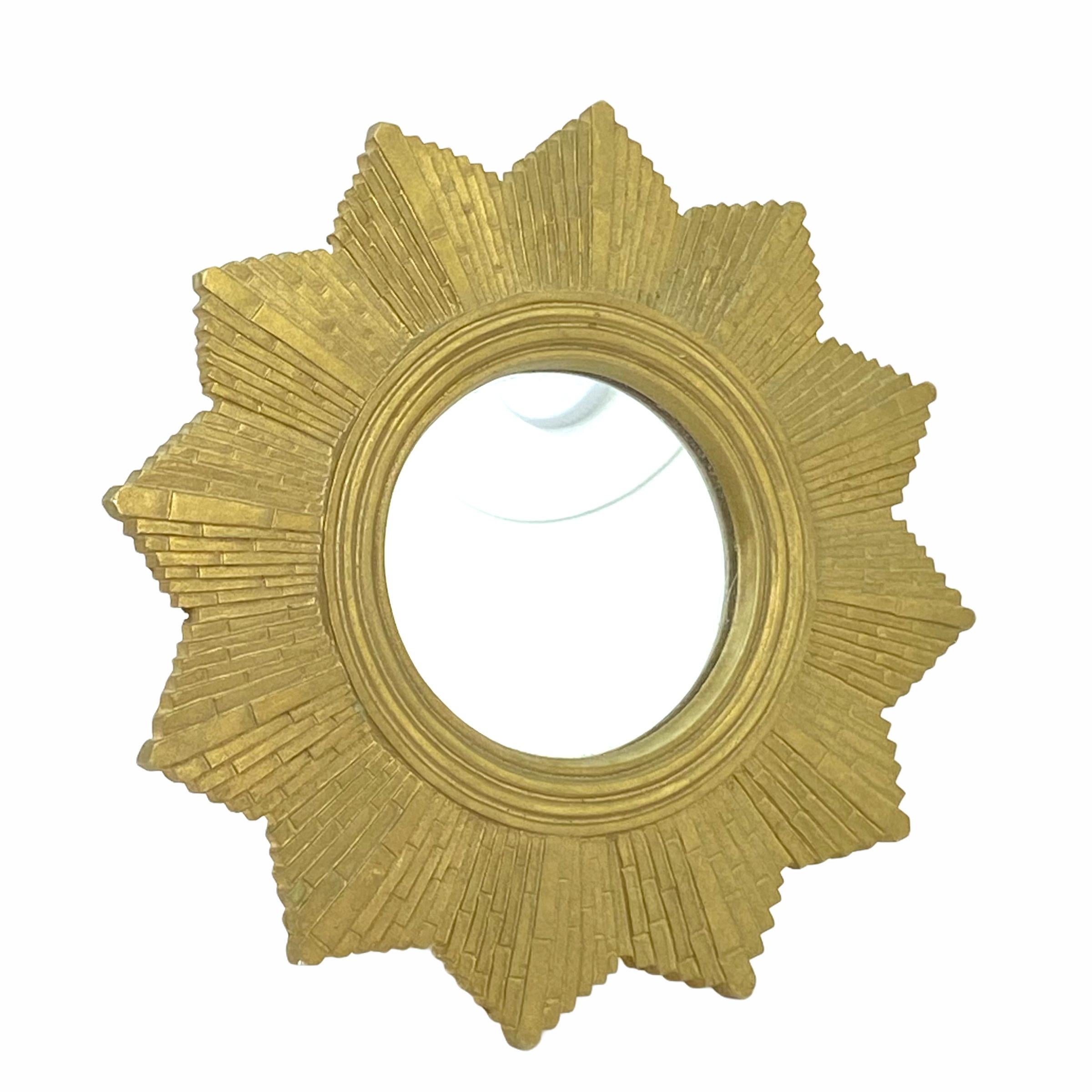 Un joli miroir en forme de soleil ou d'étoile. Réalisé en composition dorée. Il mesure approximativement : 7 1/8
