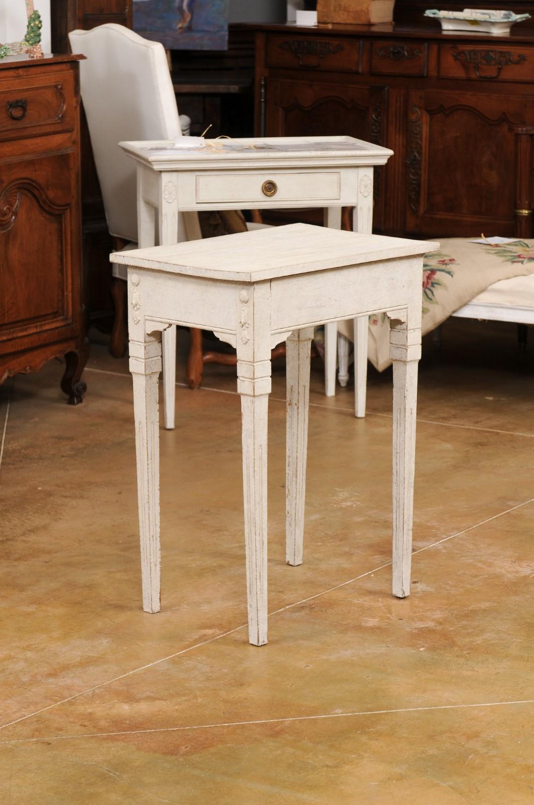A petite Swedish painted wood console table from the late 19th century with two drawers, carved motifs and fluted tapering legs. Created in Sweden during the later years of the 19th century, this petite console table features a rectangular top