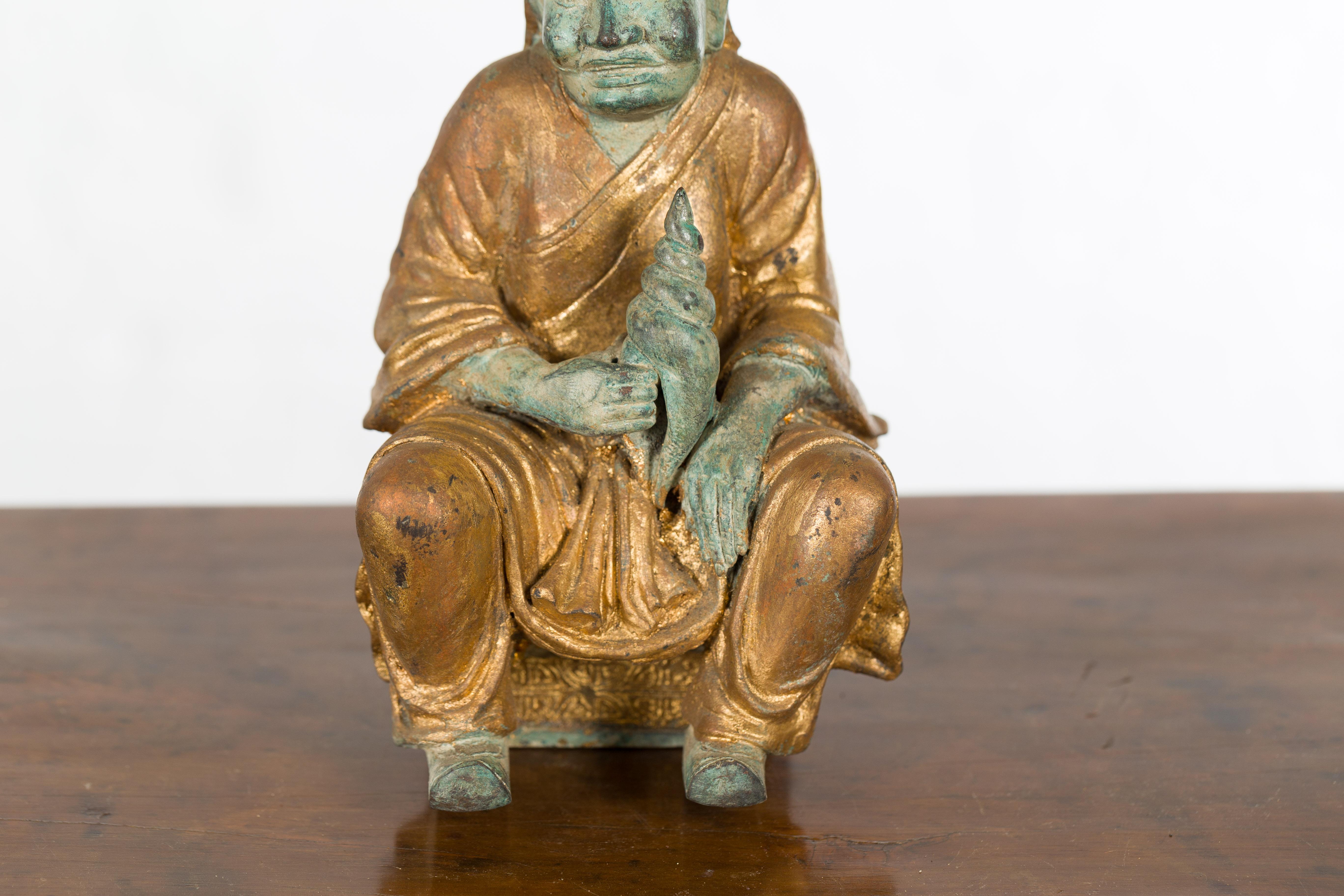 Bronze Petite Thai Verde and Gilded Statuette of a Seated Monk Holding a Conch Shell