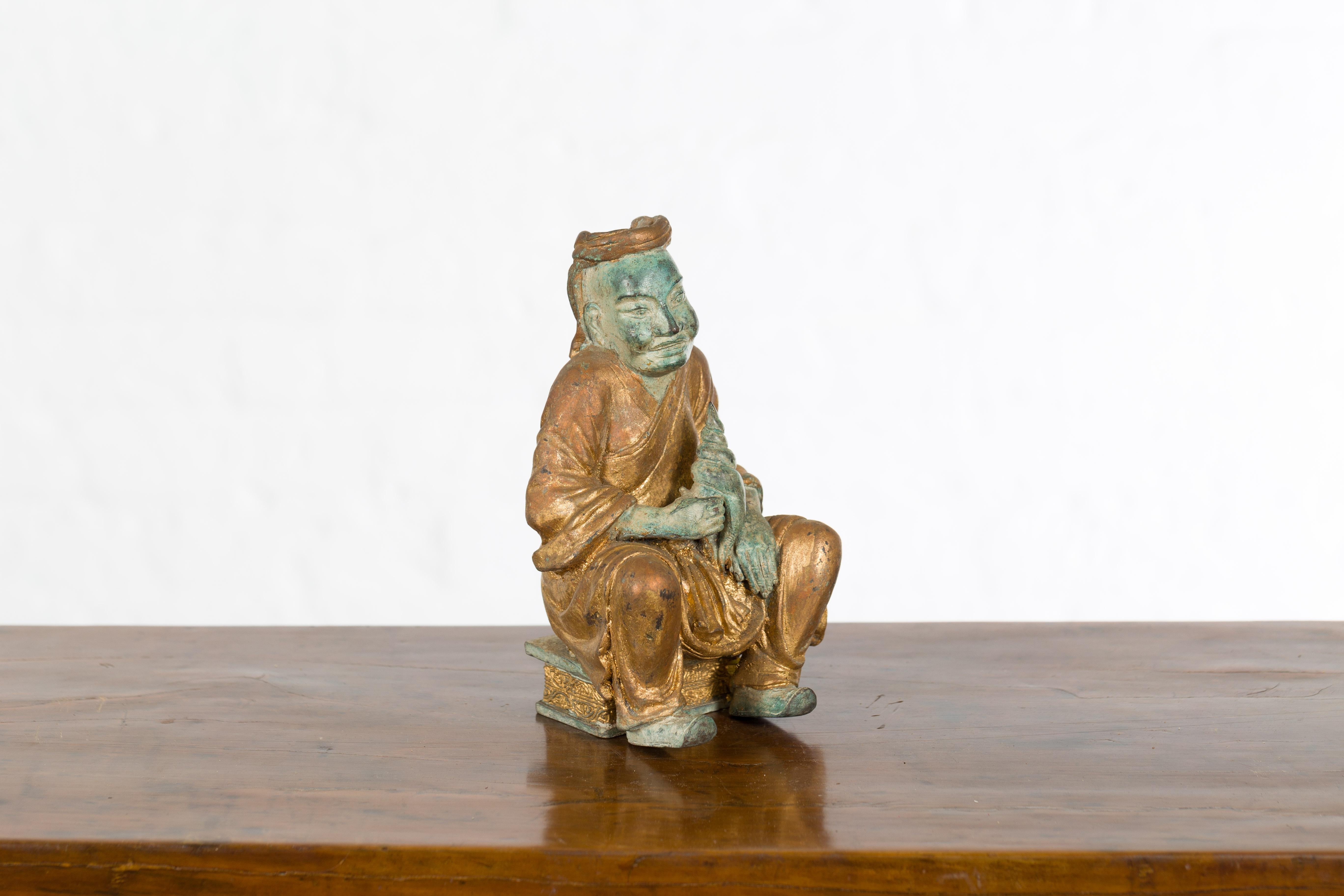 Petite Thai Verde and Gilded Statuette of a Seated Monk Holding a Conch Shell 1