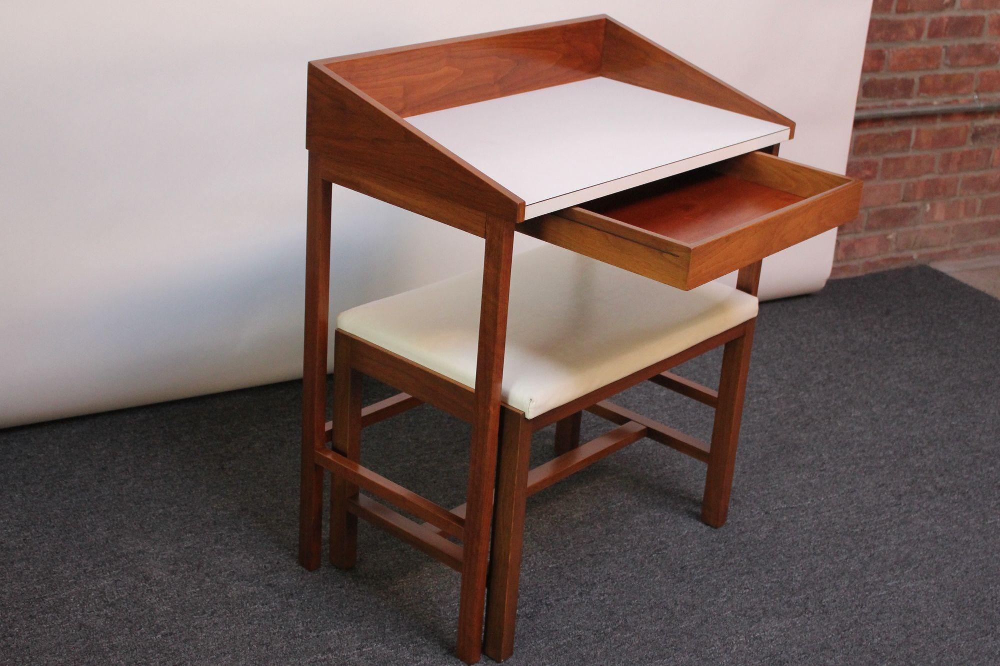Vintage mahogany vanity/writing table with corresponding naugahyde stool designed by Edward Wormley for Dunbar (ca. 1950s, Indiana, USA).
Angular form with triangular edges and white laminate surface above a single drawer for storage. 
When not in