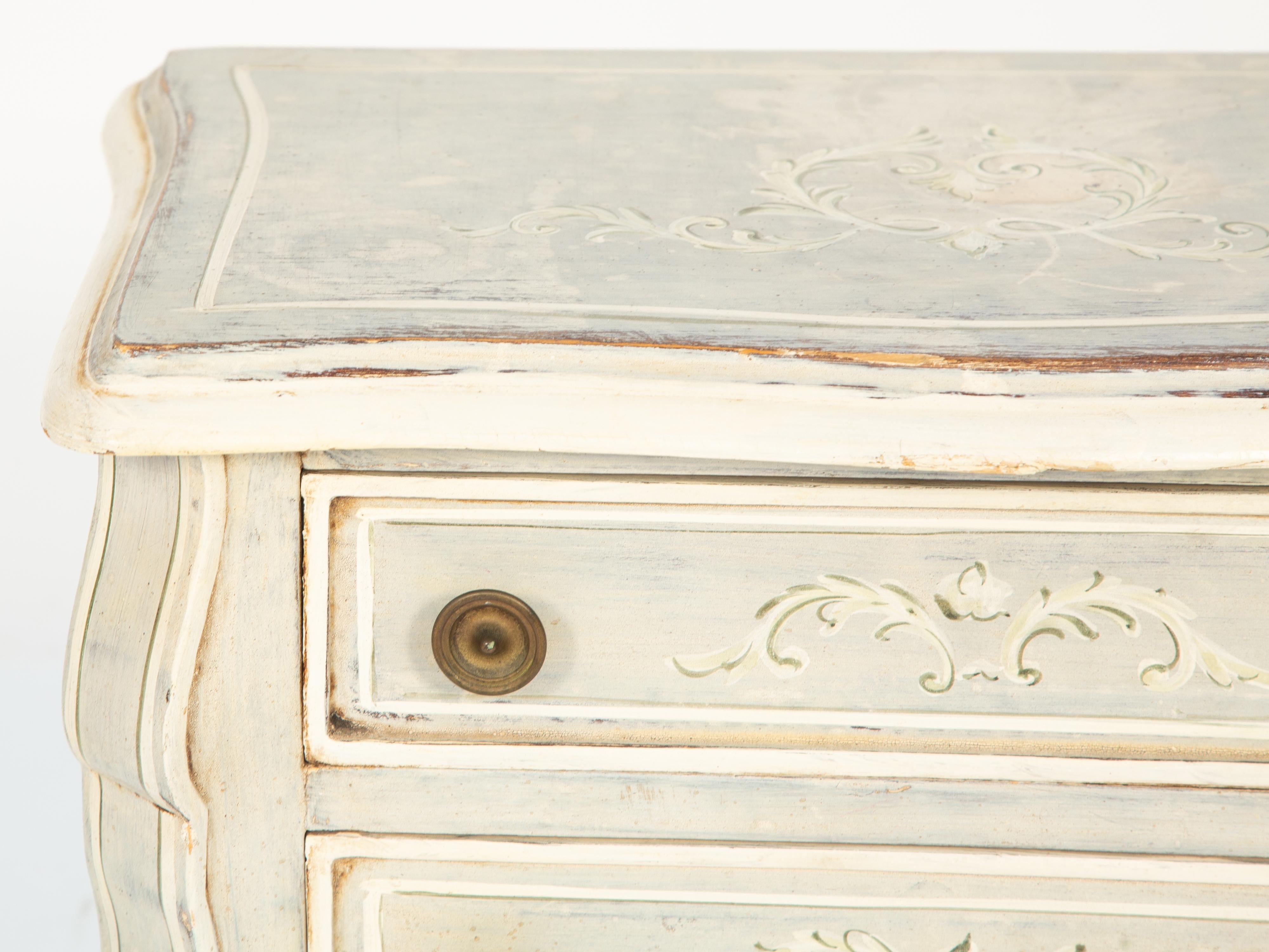 Petite commode side table, having a shaped, molded top over triple staked drawers, flanked by serpentine stiles, raised on bracket feet; its top, sides, back and drawers with original mottled finish decorated by hand painted scrollwork.

Stock ID: