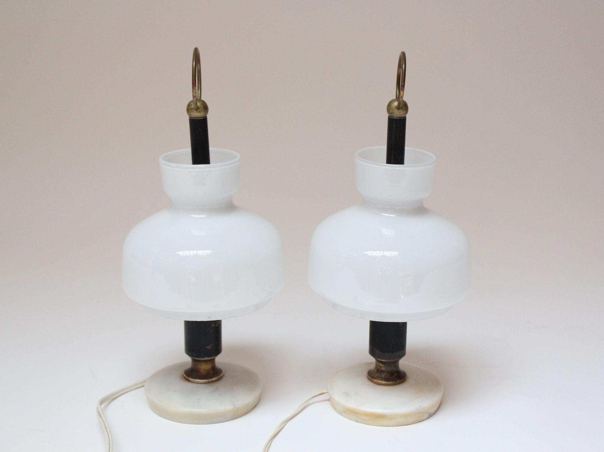 Pair of charming, petite bedside/table lamps (ca. 1950, Italy). Composed of sculptural cased white glass shades with black lacquered metal stems, brass accents, and round, marble bases.
Reminiscent of the Arenzano table lamp by Ignazio Gardella, but