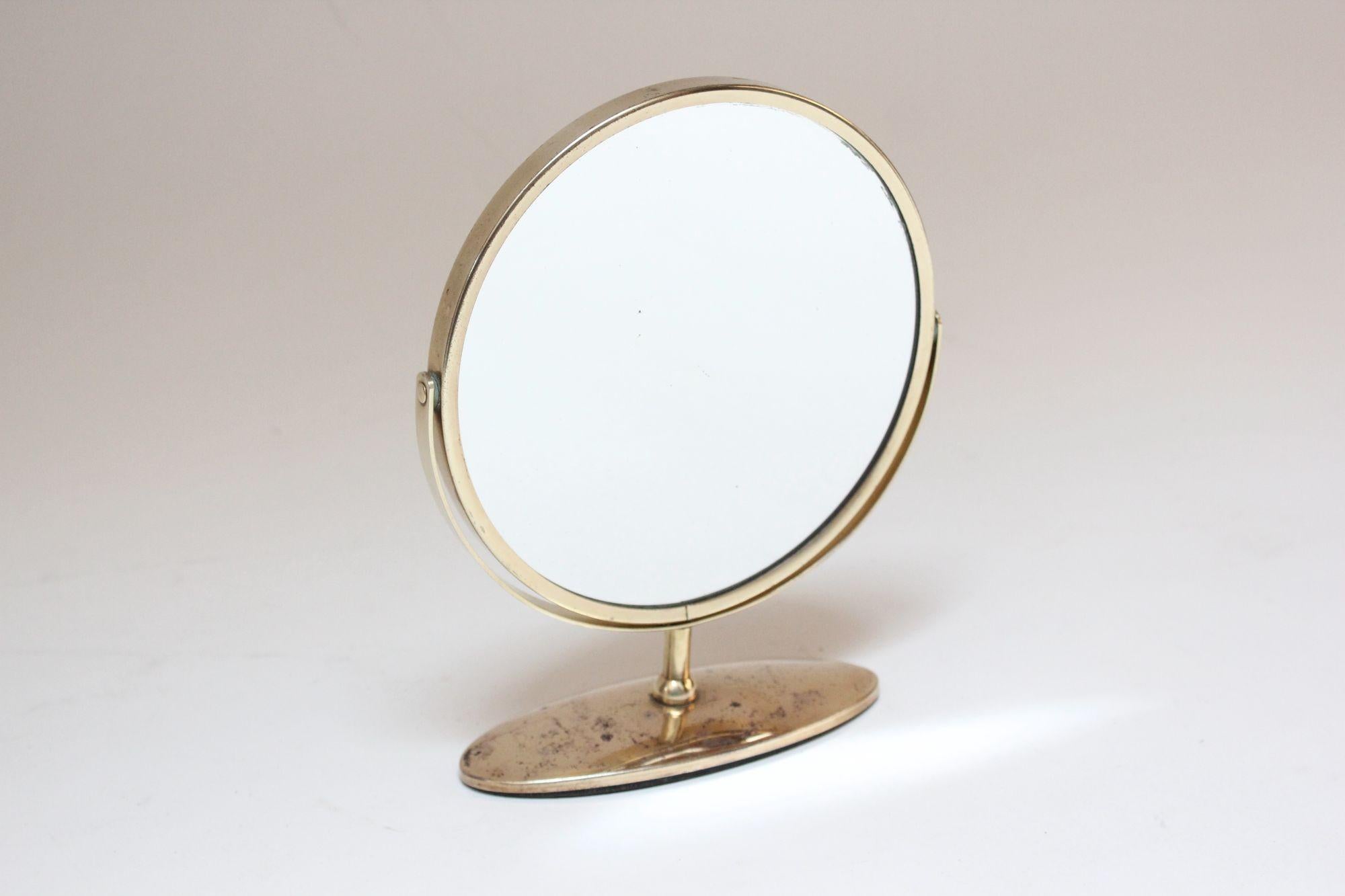 Elegant and petite table/vanity mirror in brass (ca. 1950s, USA).
Mirror has two glass sides and can swivel from one to the other.
Brass has been newly polished but tarnish spots remain (largely to the base) as shown.
The mirror glass on both sides