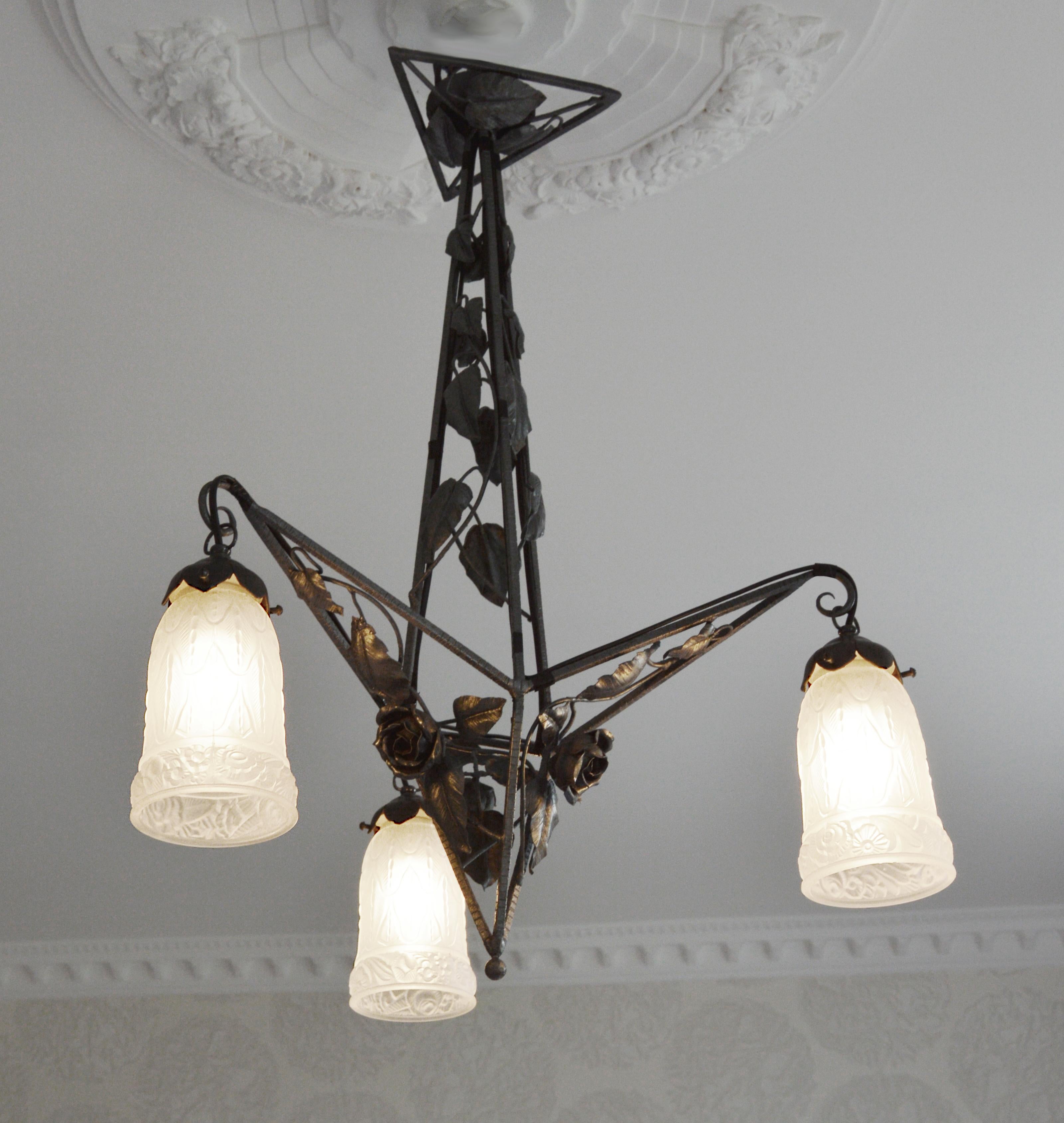 French Art Deco chandelier by Petitot (Paris), France, circa 1925. Frosted glass and wrought iron. 3 stylized frosted glass shades. Wrought iron fixture. Size: Height 26.4