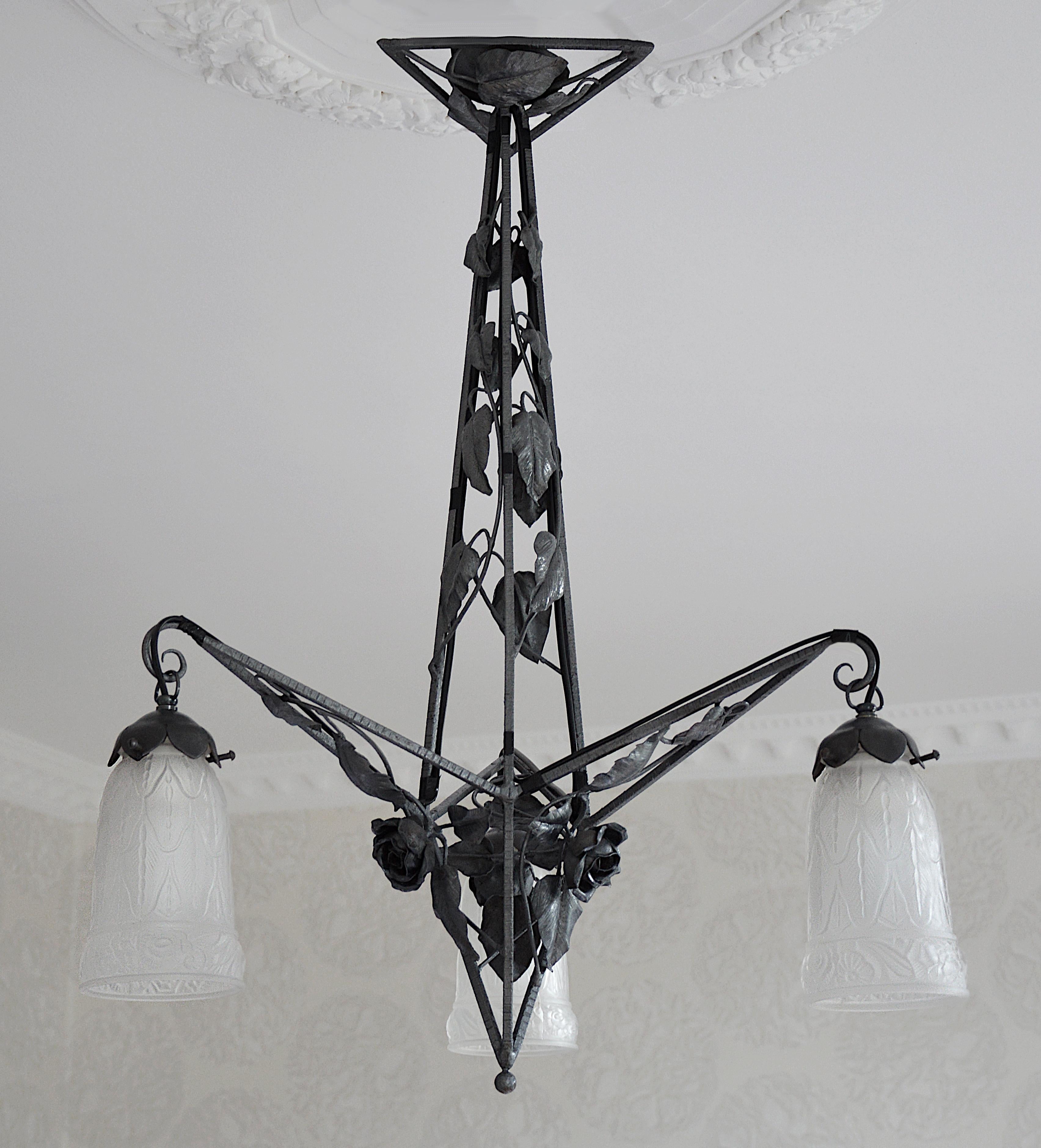 French Art Deco chandelier by Petitot (Paris), France, circa 1925. Frosted glass and wrought iron. 3 stylized frosted glass shades. Wrought iron fixture. Size: Height 26.4