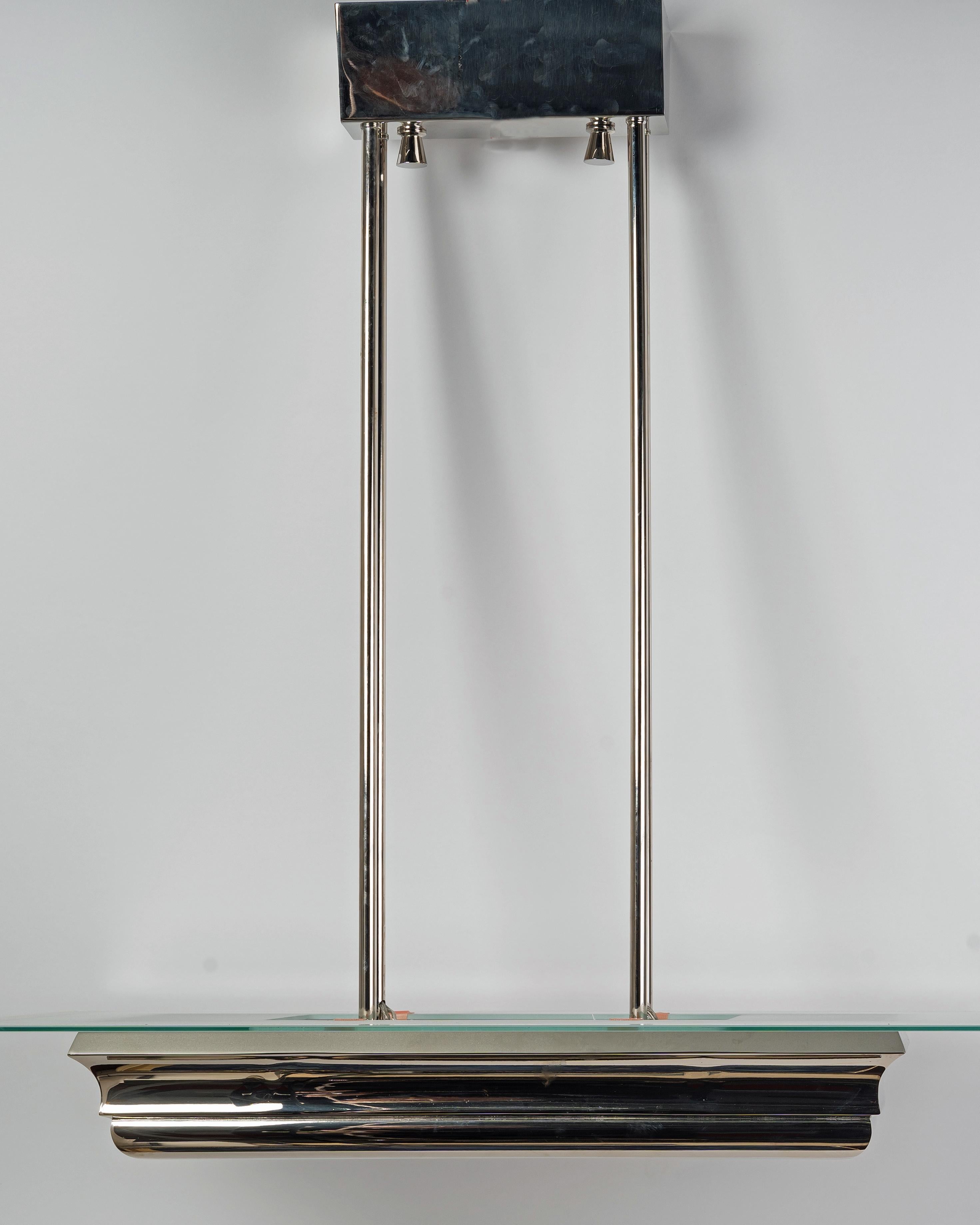 Lustre Art Déco en bronze nickelé datant des années 1930 par l'Atelier Petitot.

La partie inférieure du corps du lustre est constituée d'un cadre rectangulaire nickelé. 

Il y a une plaque de verre sablé en bas et une plaque de verre sablé avec des