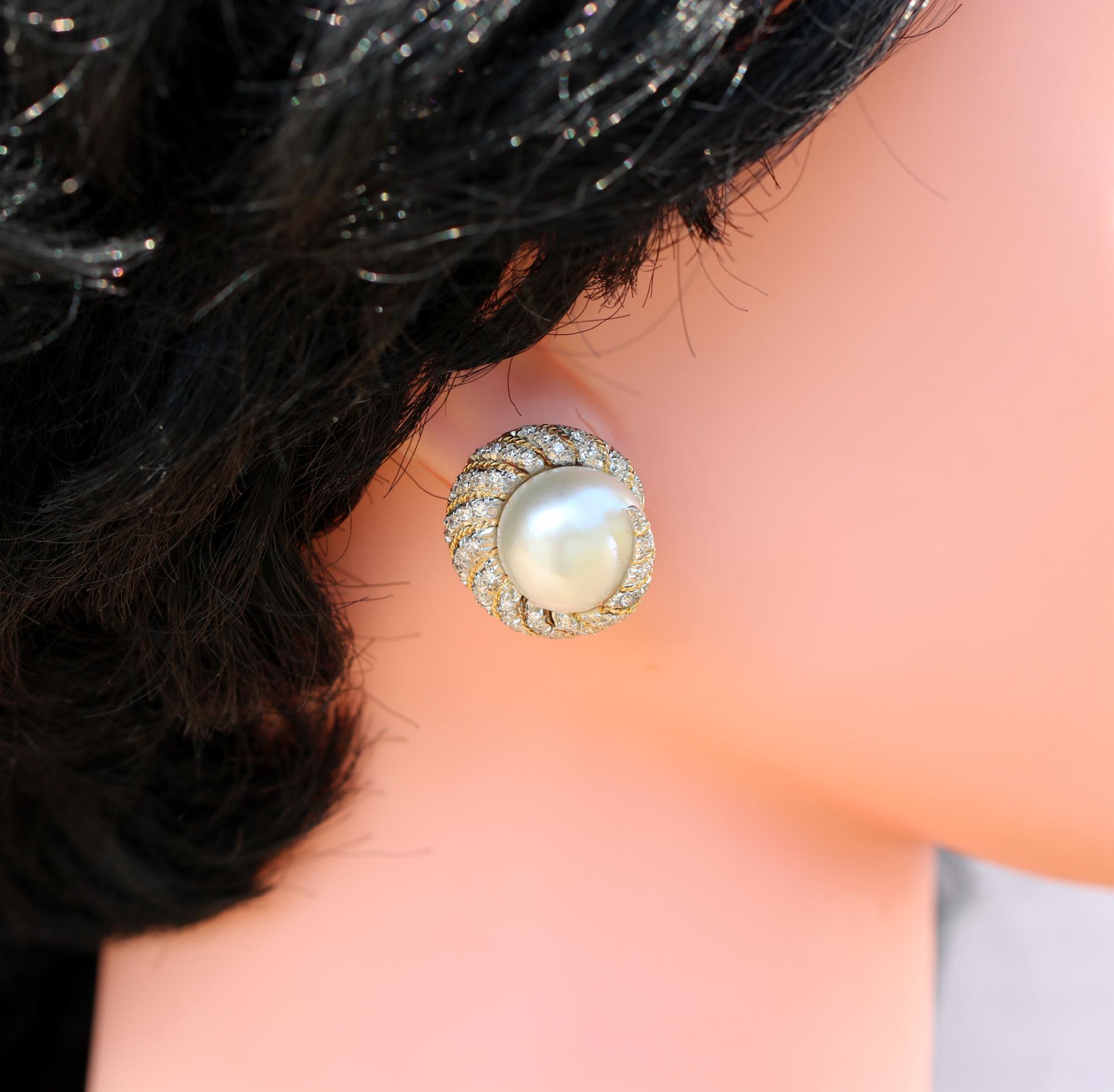 A pair of 18K white gold earrings borrowing design cues from the sea, with a nautilus like style. At the center of each earring is an approximately 15mm large South Sea pearl. Wrapping around the pearls are a combined total of approximately 1.40ct