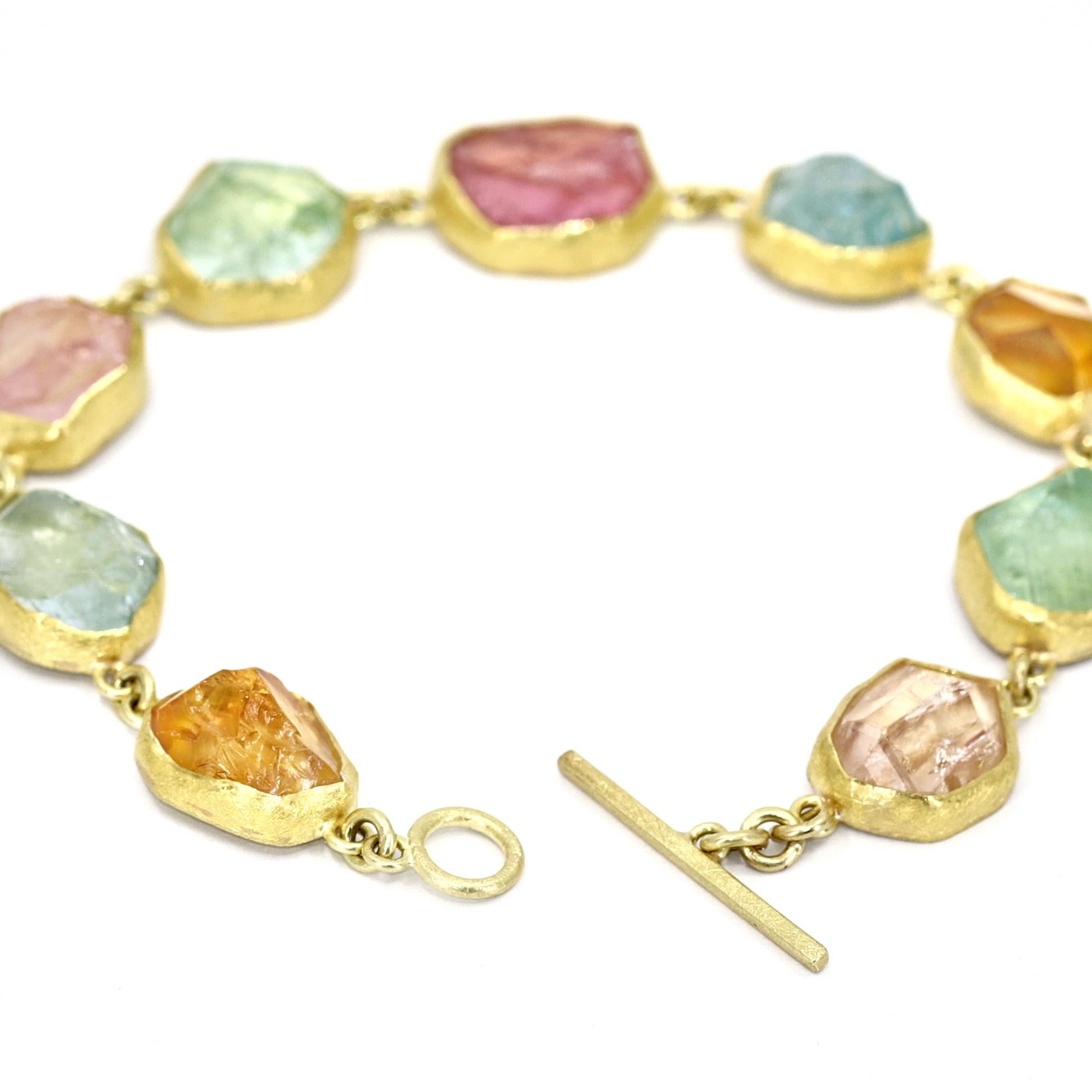 A one of a kind, wearable work of art by acclaimed jewelry maker Petra Class, the 'In the Rough' Bracelet is handmade in signature-finished 22k yellow gold and showcases an assortment of aquamarine, citrine, Imperial topaz, green tourmaline, and