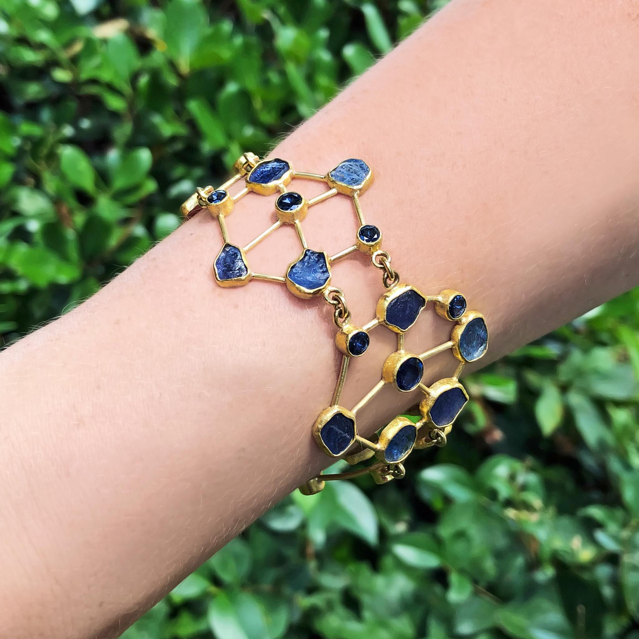 A one of a kind, wearable work of art by acclaimed jewelry maker Petra Class, the Pinwheels Bracelet is handmade in signature-finished 22k yellow gold and showcases 4.31 total carats of round faceted blue Montana sapphire and 22.70 total carats of