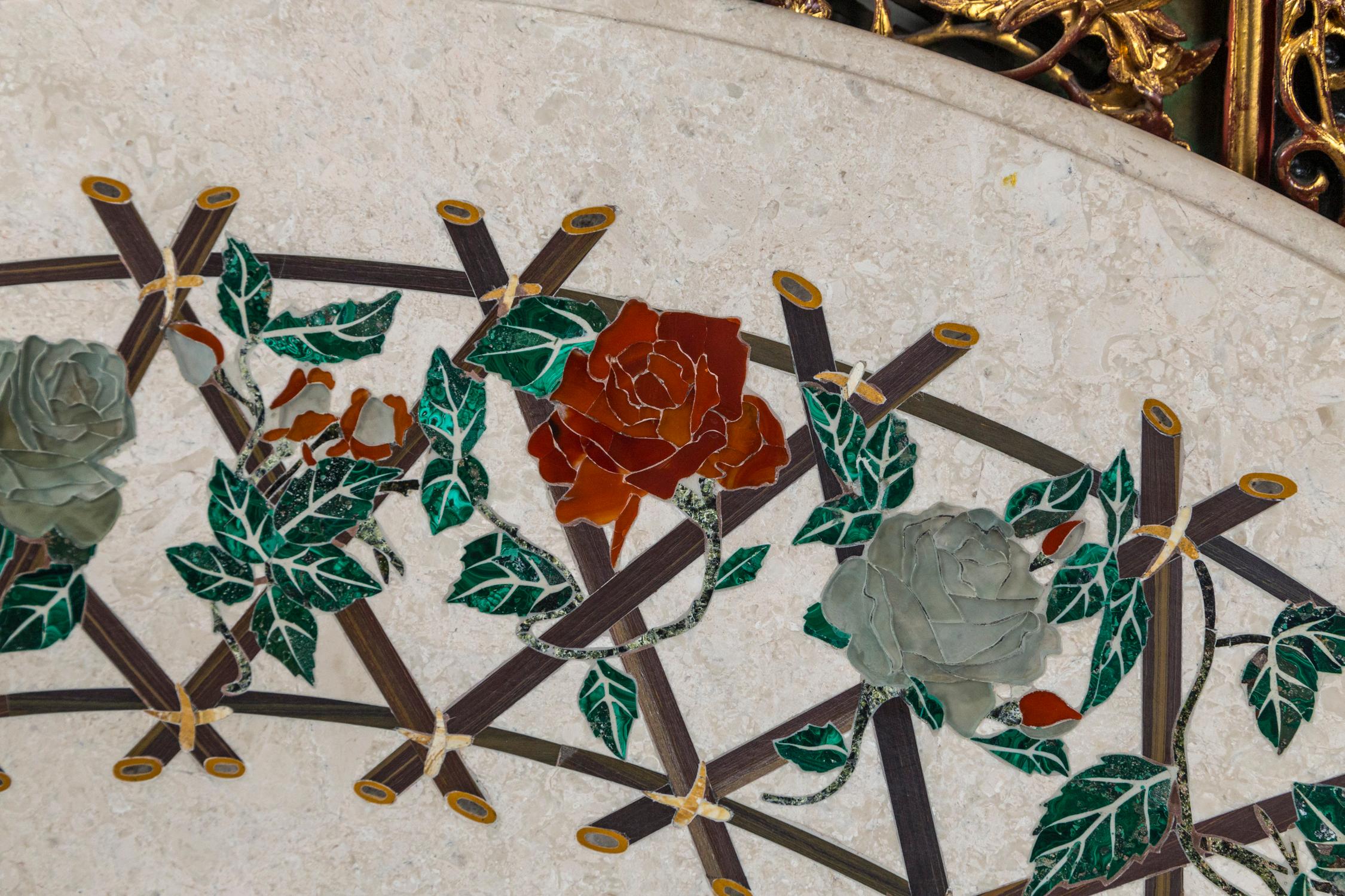 The white ground marble inlaid with 2 concentric circles of reddish flowers, green leaves and a criss cross lattice work. Measure: 48