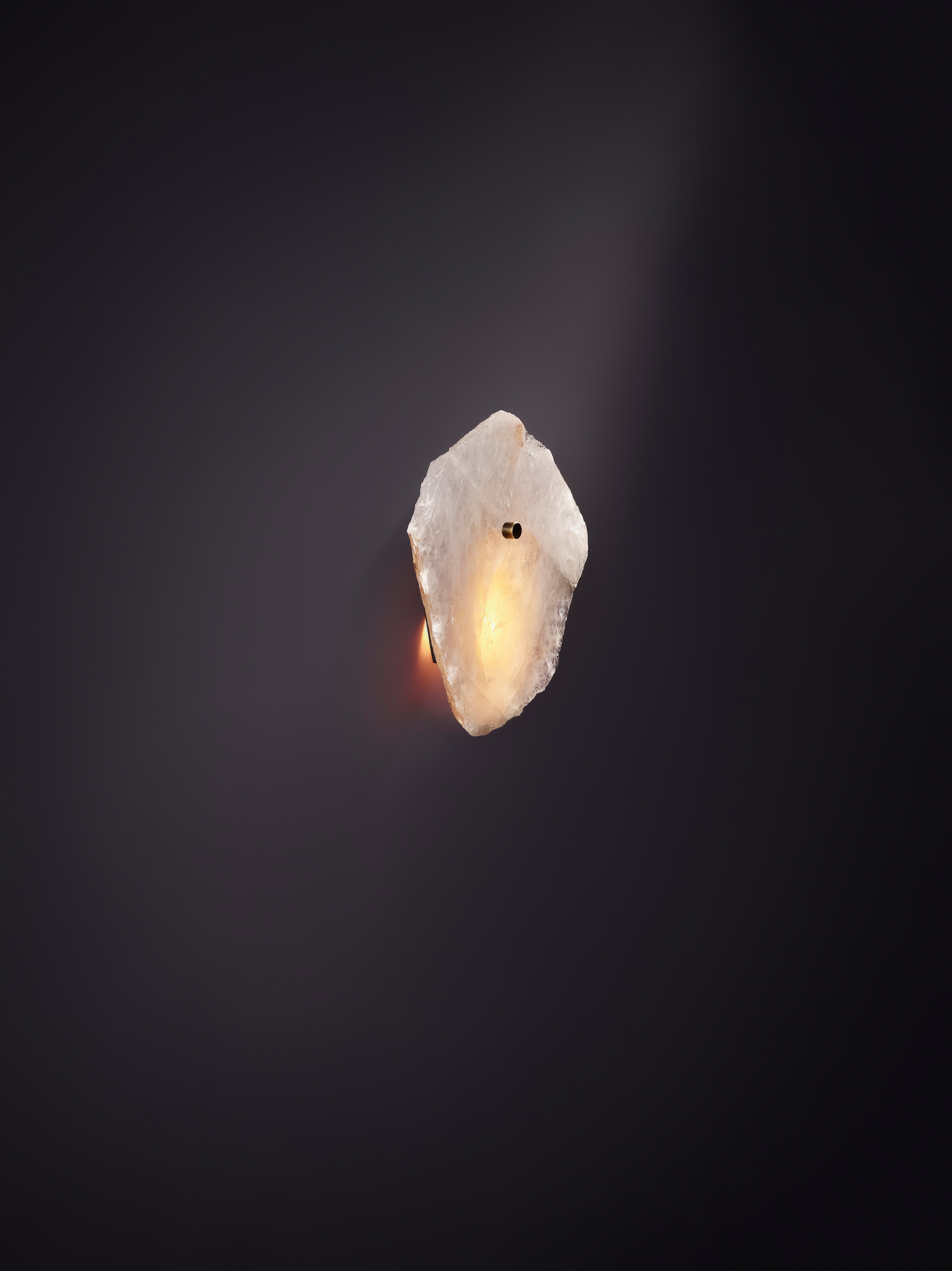 Petra I Mono Clear Quartz Sconce by Christopher Boots
Dimensions: D 10 x W 30 x H 30 cm.
Materials: Aged brass, slices of polished clear quartz.

Available in clear, rose, or smoky quartz. Please contact us.

PETRA (from the Greek word Πέτρα,