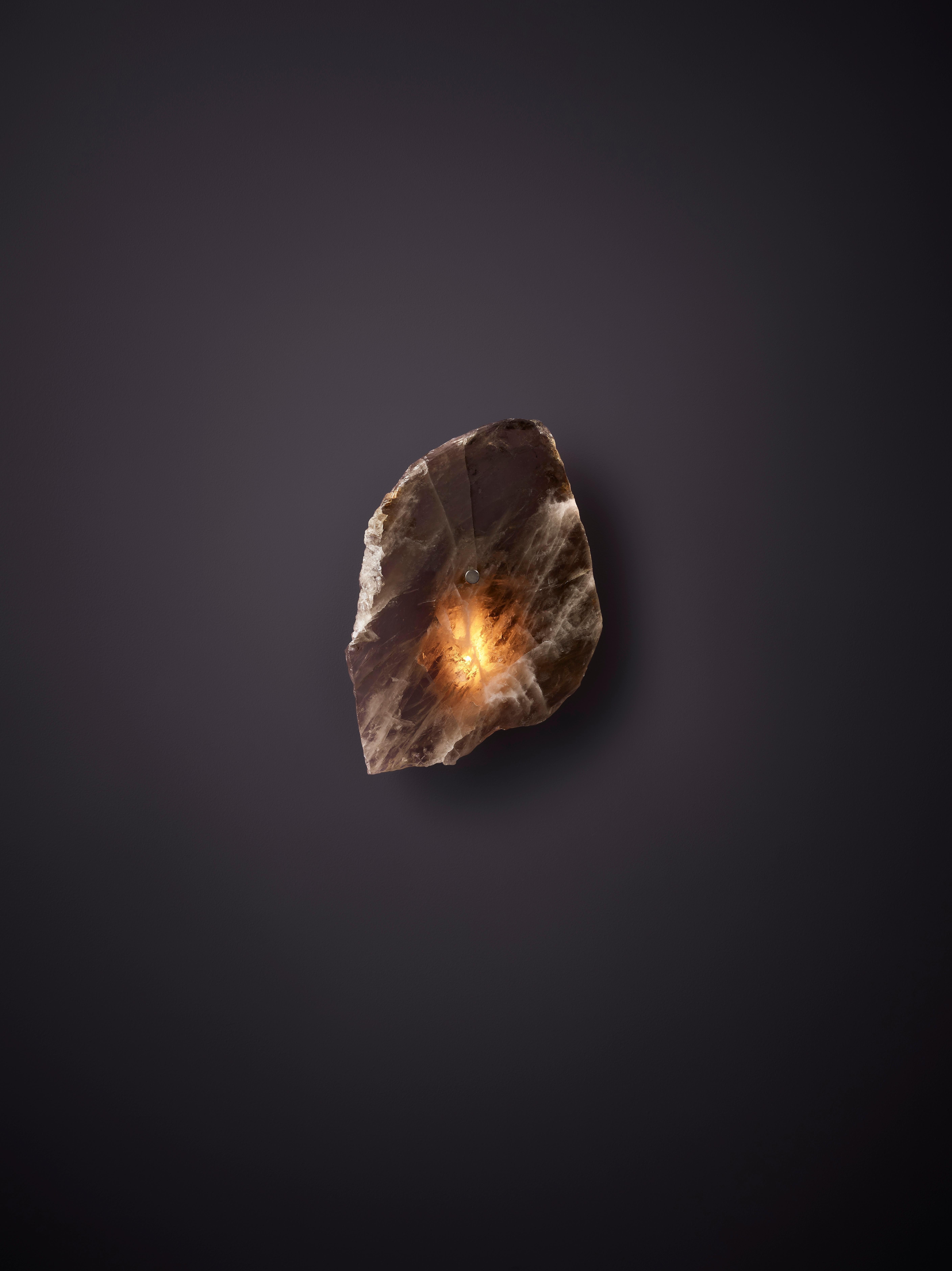 Petra I Mono Smoky Quartz Sconce by Christopher Boots
Dimensioni: D 10 x L 30 x H 30 cm.
Materiali: Ottone invecchiato, fette di quarzo fumé lucidato.

Disponibile in quarzo chiaro, rosa o fumé. Contattateci.

PETRA (dalla parola greca Πέτρα, che