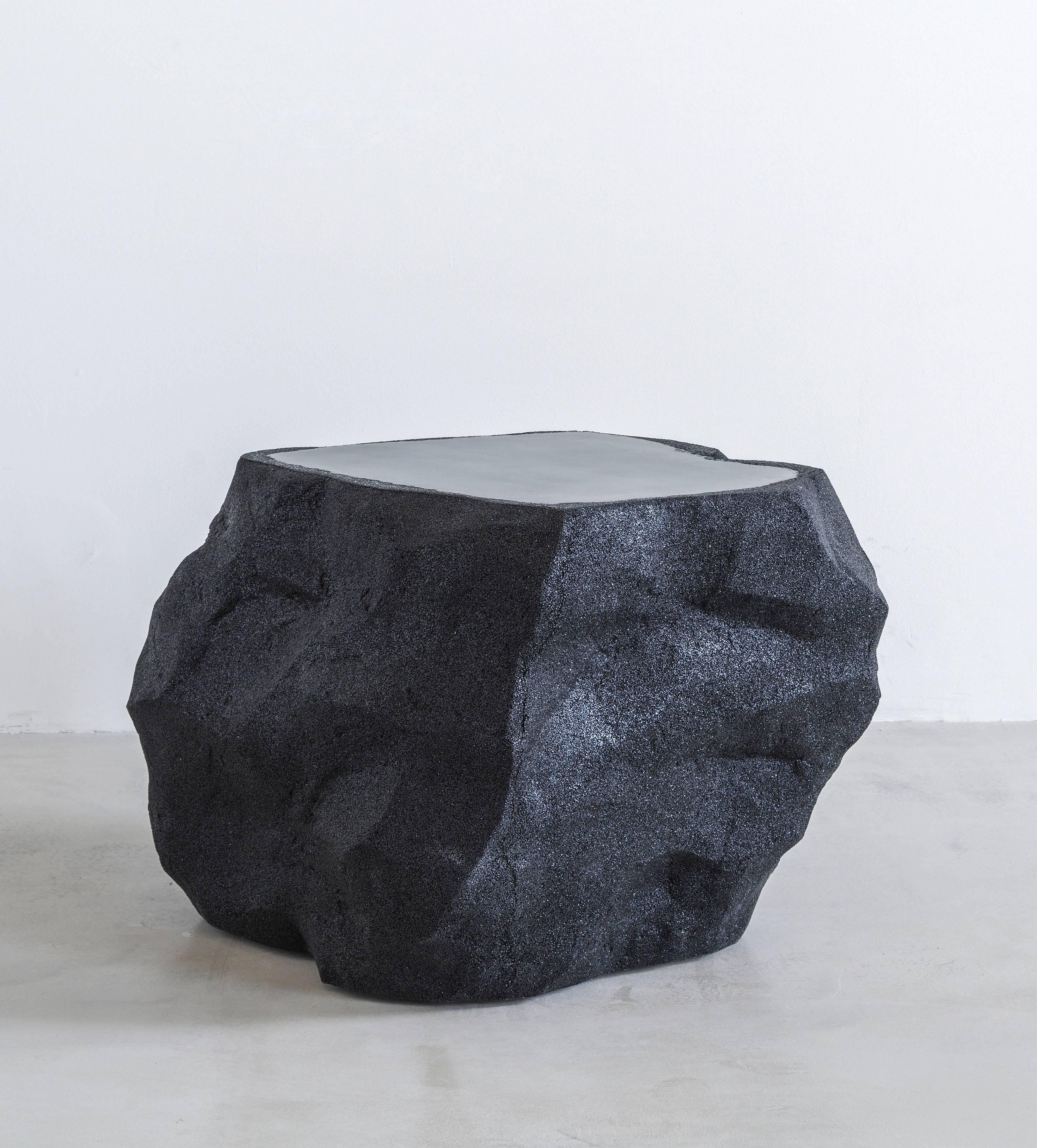 Composed from cement and silica, the jagged structure creates a surface of texture and smoothness reminiscent of a slab of earth. The piece maintains an organic, terrain-like sensibility through the hand-formed black materials, in strict contrast to