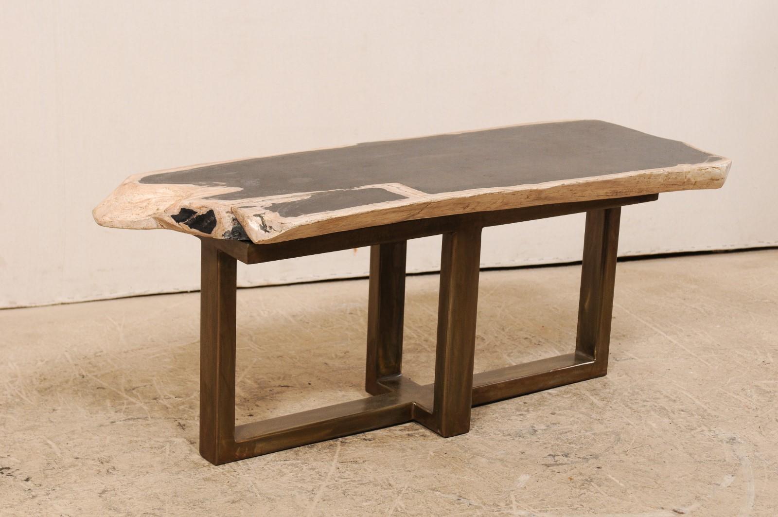 Une table basse (ou un banc) au design moderne et au plateau en bois pétrifié. Cette table basse sur mesure a été fabriquée à partir d'une magnifique dalle épaisse de bois pétrifié poli, de forme rectangulaire et d'une longueur d'un peu plus d'un