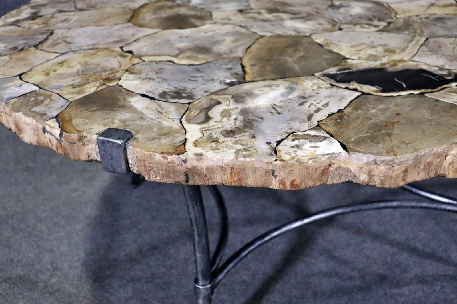 Round coffee table with a mosaic style top made of petrified wood, set on an iron leg base.
Please confirm location NY or NJ