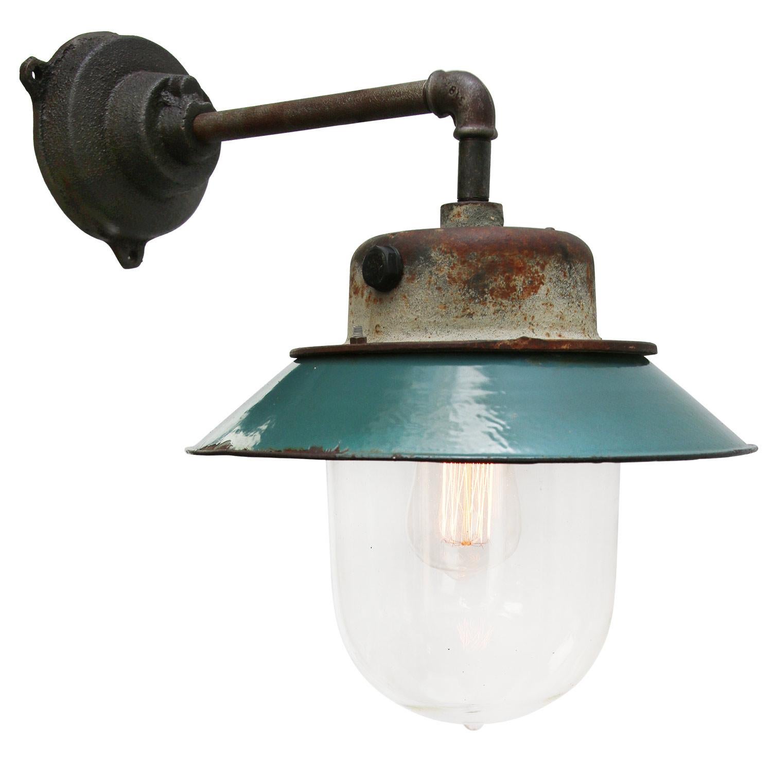 Petrol enamel industrial wall lamp with white interior.
Petrol cast aluminium top, cast iron arm
Clear glass 

Diameter cast iron wall piece: 12 cm. Three holes to secure.

Weight: 4.00 kg / 8.8 lb

Priced per individual item. All lamps have
