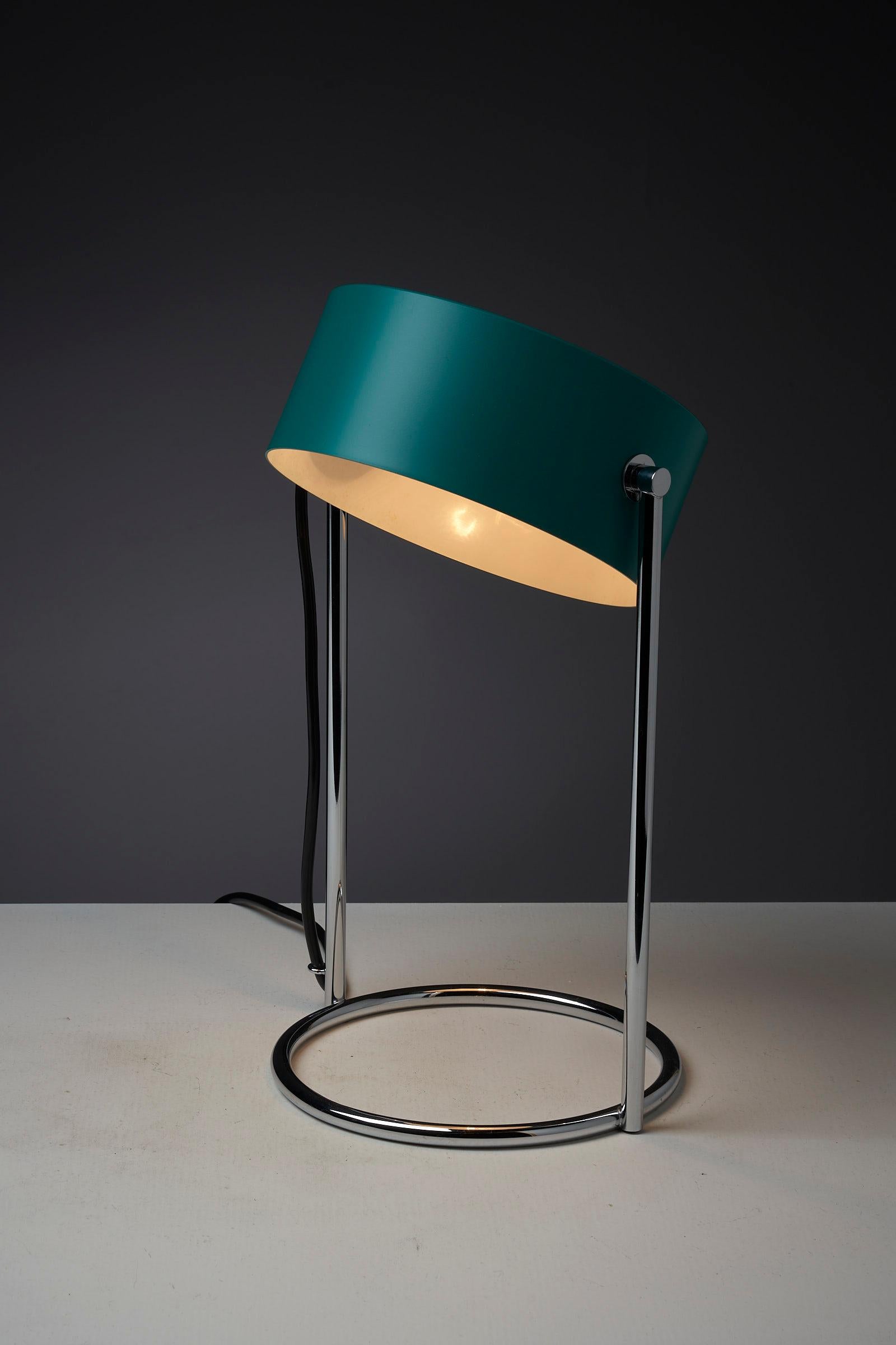 This is an elegant table lamp in stunning condition, featuring a petrol green shade made of lacquered metal that is fully adjustable around its axis. The shade is complemented by a chromed metal base, which perfectly matches its color and style. The