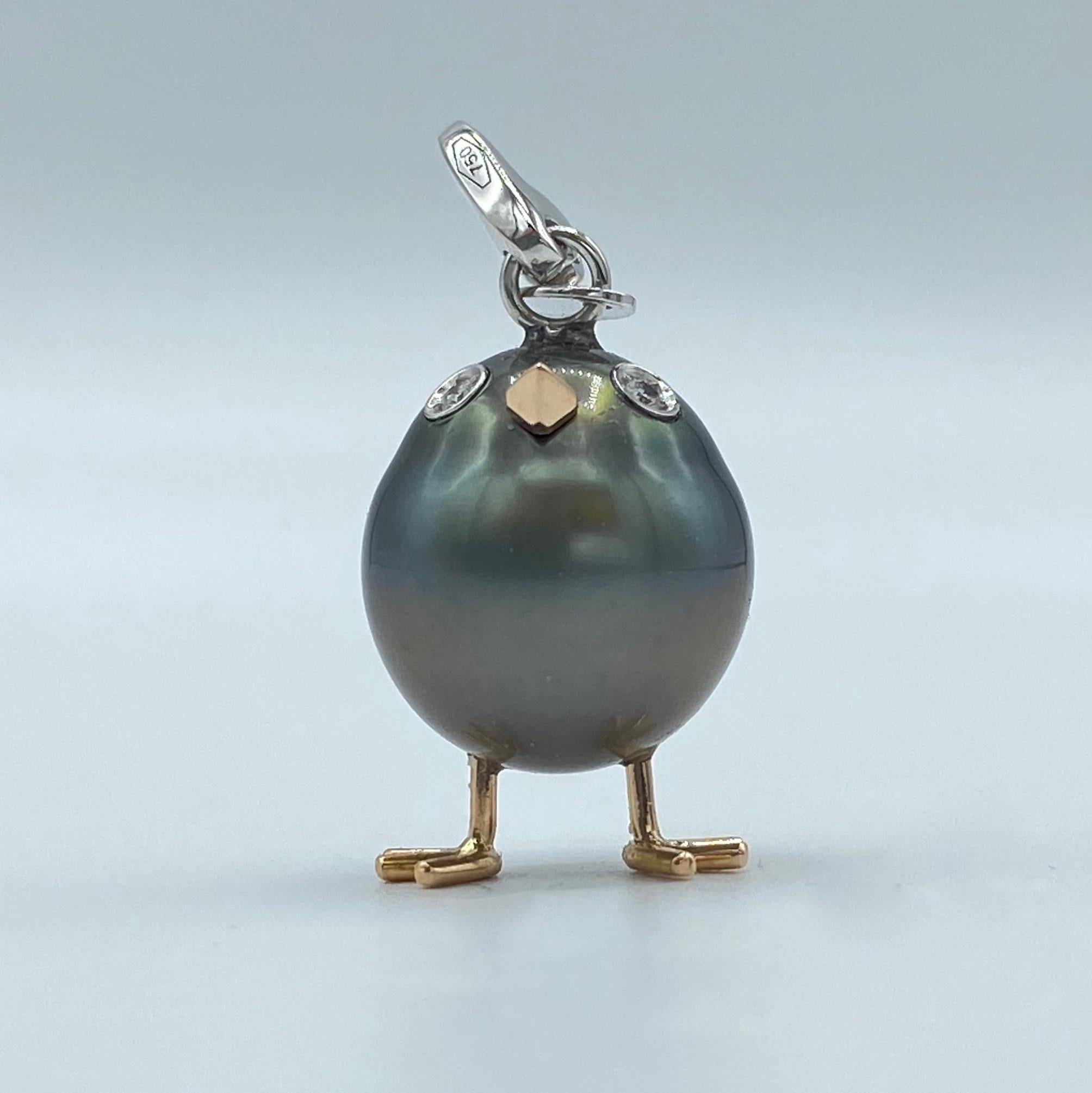 A very beautiful Tahitian pearl has been carefully crafted to make a chick. He has his two legs, two eyes encrusted with two white diamonds and his beak. 
The gold is white for the eyes and the carabiner, for the other particulars it's red.
The